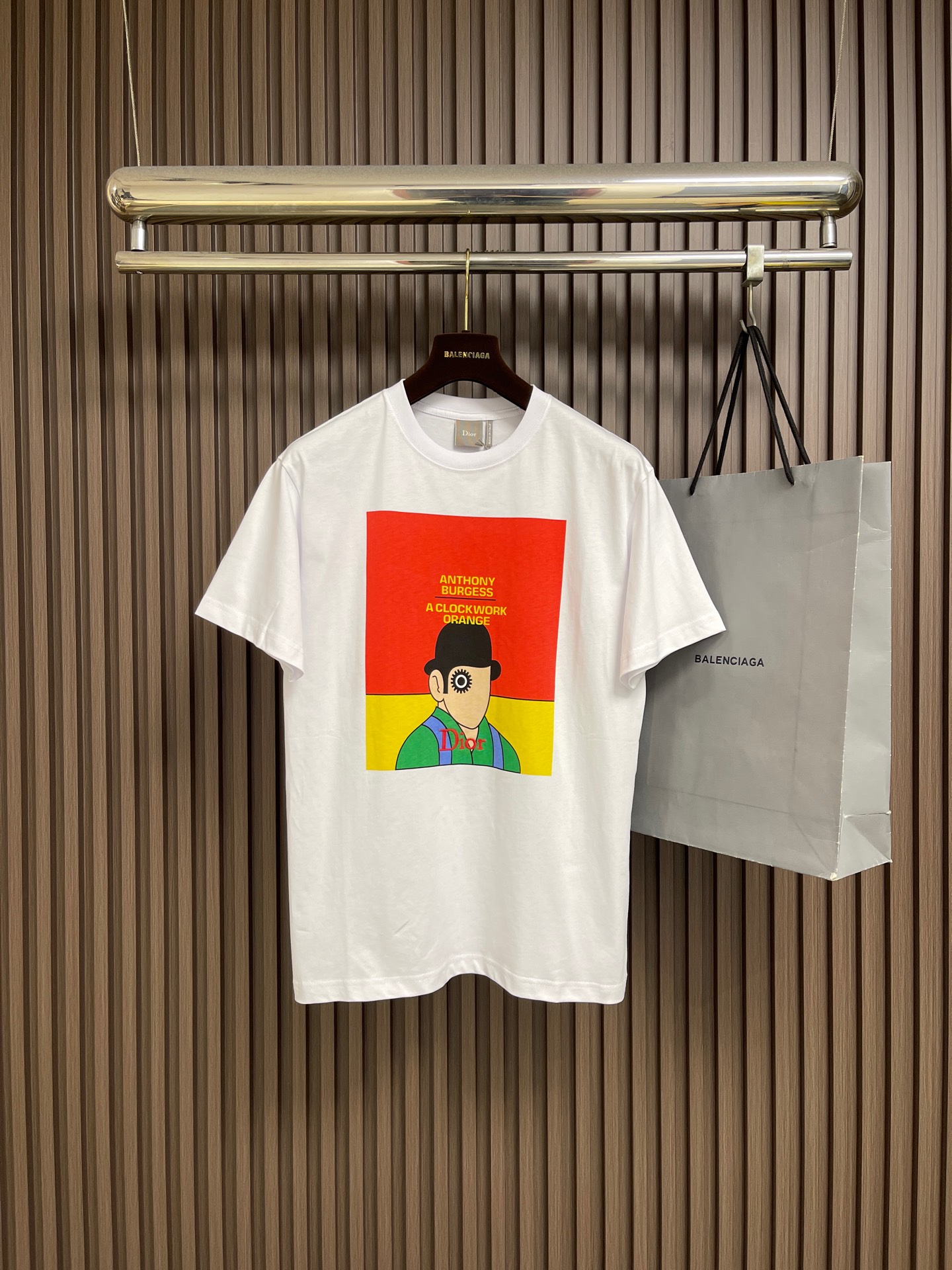 NO:847344,Dior The clockwork cover round neck short-sleeved T-shirt is made of 15-count special-spun compact cotton, 230gm pure cotton plain fabric, with 32-count 1×1 rib, 340gm. The 15-count special-spun compact cotton is a medium-low yarn count, and the yarn is thicker. The special-spun compact spinning process significantly reduces yarn hairiness, making the Thick-count yarn can also present a delicate and slightly matte cloth texture, while greatly improving the anti-pilling level. 32-count fine yarn combined with ultra-high weight makes the neckline extremely dense and thick. The front is decorated with the original cover pattern of 'A Clockwork Orange' using a penetration printing process; while specific letters are flat Penetration printing is essentially dye printing. Special additives are used to completely penetrate the dye molecules into the interior of cotton fibers and covalently bond with the fibers. Penetration printing requires high-precision color separation plate making to decompose the cover image into multiple color plates; printing During the process, dyes of various colors are sequentially scraped onto the fabric through the screen and solidified under the action of high-temperature steam. Penetration printing has extremely high color fastness and will not crack or fall off after washing, and will naturally become old along with the cotton fibers. The overall wiring is straight and delicate, the fabric is comfortable and soft, and the color is consistent without color difference. It can be matched with the same style to create a fashionable look, and can be used in various occasions. Customized accessories, complete with three standards, same style for men and women! Size XS-L19860909Dior 发条封面圆领短袖t恤,选用了15支特纺紧密棉,230gm的纯棉平纹面料,搭配32支1×1罗纹,340gm.15支特纺紧密棉属于中低纱支,纱线较粗.特纺紧密纺工艺显著减少了纱线毛羽,使粗支纱线也能呈现出细腻且微雾面的布面质感,同时大幅提升抗起毛球等级.32支细纱配合超高克重,使得领口极其致密厚重.正面饰以《发条橙》原版封面图案采用了渗透印花工艺；而特定字母则采用平针立体刺绣并以定位刺绣方式呈现渗透印花本质上是染料印花,通过特殊助剂使染料分子完全渗入棉纤维内部,与纤维发生共价键结合.渗透印花需要通过高精度分色制版,将封面图像分解为多套色版；印花过程中,各色染料依次通过丝网刮印到面料上,在高温蒸汽作用下固色.渗透印花的色牢度极高,水洗后不龟裂、不脱落,且会随着棉纤维一起自然做旧.整体走线平直细腻,面料舒适柔软,颜色一致无色差 能与同款搭配营造时尚造型,驾驭各种场合,定制辅料,三标齐全,男女同款！尺码XS-L XS码胸围102肩宽47衣长70 S码 胸围106肩宽48.5衣长72 M码胸围110 肩宽50衣长74 L码 胸围114 肩宽51.5 衣长76,,dior,T-shirt,tees，t-shirt,,Men's clothing