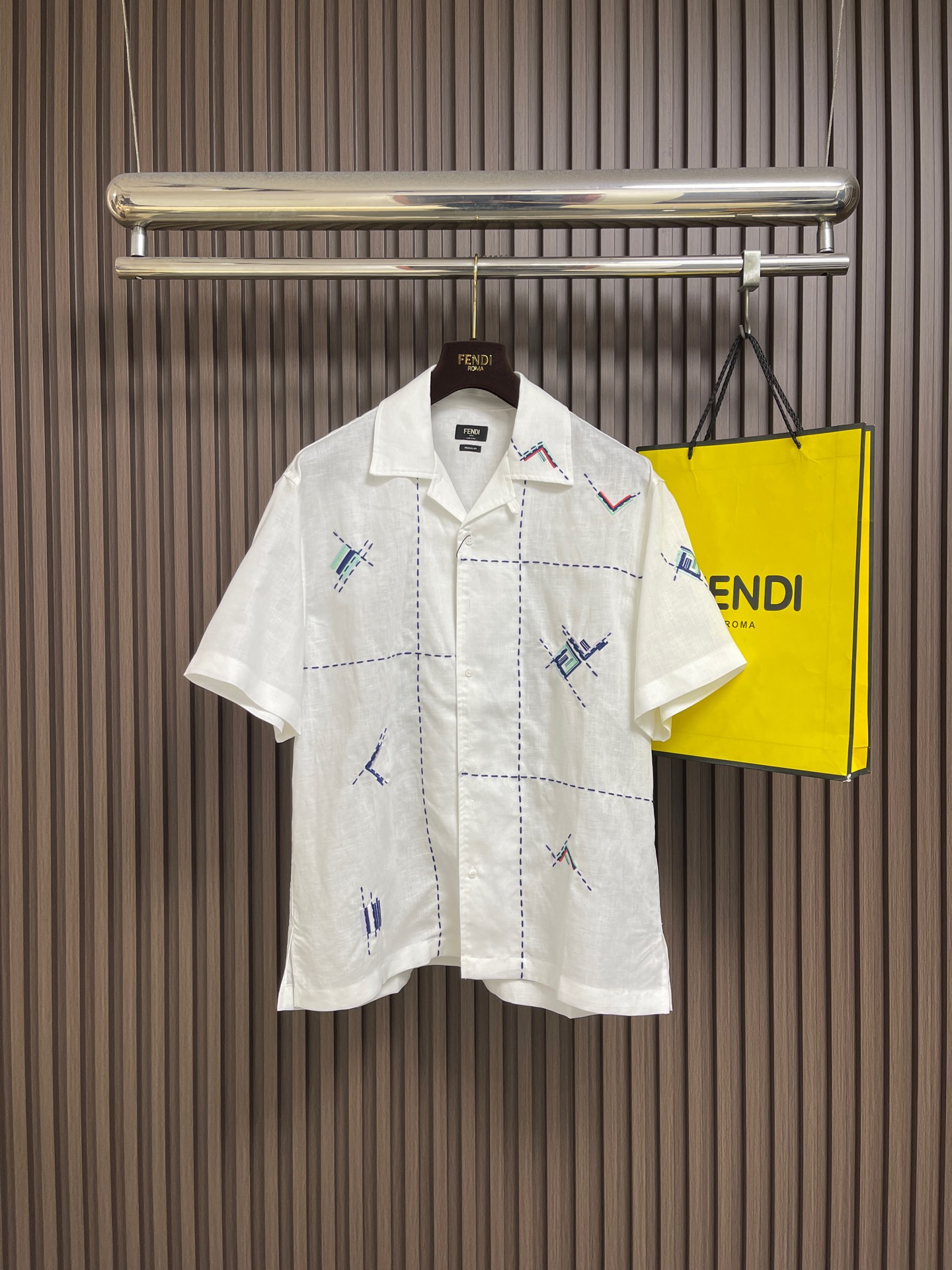 NO:845115,Fendi line embroidery pattern short-sleeved shirt, FENDI white short-sleeved shirt, with neat Cuban collar and loose tailoring, suitable for summer. The scattered geometric embroidery on the body (interweaving lines and color blocks) breaks the monotony of pure white and injects a sense of artistic deconstruction. Light and breathable fabric, casual resort street style can be switched at will. Every detail shows Italian ingenuity, allowing you to stand out in the refreshing and easily achieve a high-end casual atmosphere. Sizes S-XL S  Bust 112, Shoulder width 50.5, Length 73. Size M. Bust 116. Shoulder width 52. Length 74.5 Size L. Bust 120. Shoulder width 53.5. Length 76. Size XL. Bust 124. Shoulder width 55. Length 77.5.19860909Fendi 线条刺绣图案短袖衬衫,FENDI 白色短袖衬衫,以利落古巴领+宽松剪裁适配夏日.衣身错落的几何刺绣（线条、色块交织）,打破纯白单调,注入艺术解构感.轻薄透气面料,休闲度假街头风随心切换,每一处细节都彰显意式匠心,让你在清爽中脱颖而出,轻松拿捏高级随性氛围.尺码S-XL S码 胸围112肩宽50.5 衣长73 M码胸围116 肩宽52 衣长74.5 L码 胸围120肩宽53.5 衣长76 XL码胸围124肩宽55 衣长77.5,,fendi,shirts,T-shirt,,Men's clothing