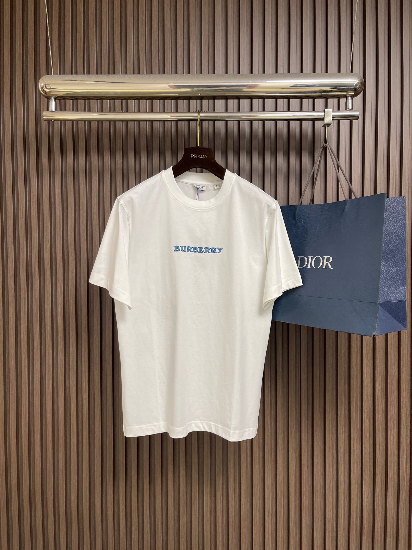 NO:845121,Burberry  The Blue Knight round-neck short-sleeved T-shirt is made of 15-count special-spun compact cotton, 230g㎡; with 32-count 1×1 rib, 340g㎡. The fabric is a heavy-weight fabric with thick needles, strong texture, and crisp texture. Because the 15-count yarn is thicker, the shaping process is particularly important. It can eliminate the internal stress generated during the weaving process of the thick-count yarn and prevent pattern misalignment due to fabric shrinkage during subsequent multi-layer printing. The collar is high-density cotton  Highly compact rib, cotton rib achieves elasticity through high-density weaving, and the touch is more pure and natural. The collection logo and the equestrian knight logo use a thick plate pulp process. The printing is repeatedly superimposed and printed on the same pattern area through a silk screen. Multiple layers of glue are printed repeatedly. The difficulty of this process lies in the alignment accuracy and thickness control of each layer. The dried pulp will accumulate on the surface of the fabric to create an obvious relief texture, which feels stiff and has a sharp outline.  .The overall wiring is straight and delicate, the fabric is comfortable and soft, and the color is consistent without color difference. It can be matched with the same style to create a fashionable look and control various occasions. Customized accessories, complete with three standards, same style for men and women!  Sizes XS-L19860909Burberry 蓝骑士圆领短袖T恤,用15支特纺紧密棉,230g㎡；搭配32支1×1罗纹,340g㎡.面料属于粗针重克重面料,肌理感强、质地挺括.由于15支纱线较粗,定形工序尤为重要,它能消除粗支纱线织造过程中产生的内应力,防止后续多层印花时因面料收缩导致图案错位.衣领属于全棉高密度紧实罗纹,全棉罗纹通过高密度织造实现弹性,触感更加纯粹自然.典藏徽标和马术骑士徽标采用的是厚板浆工艺.印花通过丝网在同一个图案区域反复叠加印刷多层胶浆.这一工艺的难点在于每层的对齐精度和对厚度的控制.干燥后的浆料会在面料表面堆积出明显的浮雕质感,手感硬挺且轮廓锐利 .整体走线平直细腻,面料舒适柔软,颜色一致无色差 能与同款搭配营造时尚造型,驾驭各种场合,定制辅料,三标齐全,男女同款！尺码XS-L XS码胸围102肩宽47衣长71 S码 胸围106肩宽48.5衣长73 M码胸围110 肩宽50衣长75 L码 胸围114 肩宽51.5 衣长77,,burberry,T-shirt,tees，t-shirt,,Men's clothing