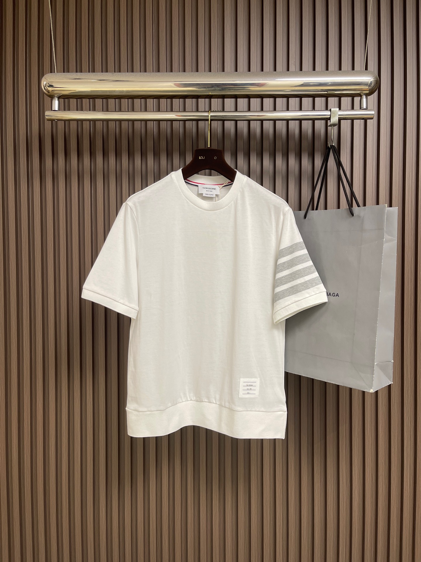 NO:847352,THOM BROWNE  Short-sleeved T-shirt with four stripes on the sleeves and arms. This T-shirt is made of 230g high-weight combed cotton knitted fabric. The surface of the fabric presents a delicate and full honeycomb texture. It feels soft and skin-friendly and has excellent breathability. It will not loosen and deform easily after being worn for a long time. The body is thin  The stitching is extremely elegant. The classic four-stripe logo on the left arm is made of high-end jacquard technology. The contrasting lines are sharp and clear, and the transition is natural and without overflowing colors. The neckline is made of warm and lustrous mother-of-pearl shell buttons, and the inner lining of the neckline is supplemented by red, white and blue three-color webbing for reinforcement.  , it is both iconic and effectively prevents neckline deformation. The placket and shoulder seams are made of double-needle hemming technology, and the stitches are fine, even and neat without losing threads; the hem adopts a classic arc design with short front and long back, and the slits on both sides are decorated with two metal buttons on each side.  It is equipped with the iconic red, white and blue webbing backing, and the brand's exclusive small logo is sewn on the inside of the hem. Every craftsmanship detail demonstrates the exquisite craftsmanship and high-end texture of high-quality garments. The overall routing is straight and delicate, the fabric is comfortable and soft, and the color is consistent with no color difference.  It can be matched with the same style to create a fashionable look, and can be used in various occasions. Customized accessories, complete with three standards, same style for men and women!  Size 1-2-3-4 1 size bust 104 shoulder width 45 length 69 size 2 bust 108 shoulder width 46 length 70 3 size bust 112 shoulder width 47 length 71 4 size bust 116 shoulder width 48 length 72,, T-shirt, tees, t-shirt,19860909THOM BROWNE 袖臂四条杠短袖T恤,这款T恤甄选230g高克重精梳棉针织面料,面料表面呈现细腻饱满的蜂巢肌理,触感软糯亲肤且具备优异的透气性,久穿不易松垮变形.衣身细节极尽考究,左臂经典的四道杠标识采用高端提花工艺,撞色线条利落分明,过渡自然无溢色；领口甄选温润光泽的珍珠母贝壳扣,领口内里辅以红白蓝三色织带包边加固,既具标志性又有效防止领口变形,门襟与肩缝处均采用双针锁边工艺,线迹细密均匀工整不脱线；下摆采用前短后长的经典弧形设计,两侧开衩处各缀两粒金属纽扣,搭配标志性红白蓝织带衬底,下摆内侧缝制品牌专属小标,每一处工艺细节都彰显出高品质成衣的精湛匠心与高级质感.整体走线平直细腻,面料舒适柔软,颜色一致无色差 能与同款搭配营造时尚造型,驾驭各种场合,定制辅料,三标齐全,男女同款！尺码1-2-3-4 1码 胸围104肩宽45 衣长69 2码 胸围108肩宽46 衣长70 3码 胸围112 肩宽47 衣长71 4码 胸围116 肩宽48 衣长72,,T-shirt,tees，t-shirt,,Men's clothing