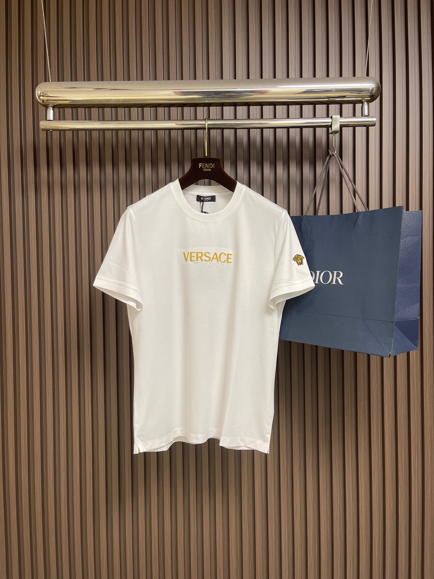 NO:848703,versace  Embroidered cotton jersey short-sleeved T-shirt. This men's embroidered cotton jersey slim fit T-shirt is made of high-count combed cotton fabric and uses jersey knitting technology to create a delicate and smooth skin-friendly texture. It has both breathability and stiffness, making the upper body comfortable and unrestricted. The iconic Medusa head on the chest is heavily crafted  Three-dimensional embroidery technology uses gold embroidery thread to outline complex textures, which are full of layers and full of luster, perfectly restoring the brand's luxury genes. Slim tailoring fits the body shape, neatly outlines the lines, the round neck design is classic and versatile, the stitching is neat and tight, and the details highlight the high-end craftsmanship. Size M-3XL  M size bust 100 shoulder width 43 length 66 L size bust 104 shoulder width 44 length 6719860909versace 刺绣棉质平纹针织短袖T恤,这件男士刺绣棉质平纹针织修身T恤,甄选高支精梳纯棉面料,以平纹针织工艺打造细腻顺滑的亲肤质感,兼具透气度与挺括感,上身舒适无束缚.胸前标志性美杜莎头像采用重工立体刺绣工艺,以金线绣线勾勒繁复纹理,层次饱满、光泽感十足,完美还原品牌奢华基因.修身剪裁贴合身形,利落勾勒线条,圆领设计经典百搭,走线工整严密,细节处彰显高端工艺水准.尺码M-3XL M码 胸围100 肩宽43衣长66 L码 胸围104 肩宽44衣长67 XL码胸围108 肩宽45衣长69 2XL码 胸围112 肩宽46衣长71 3XL码 胸围116 肩宽47 衣长73,,versace,T-shirt,tees，t-shirt,,Men's clothing