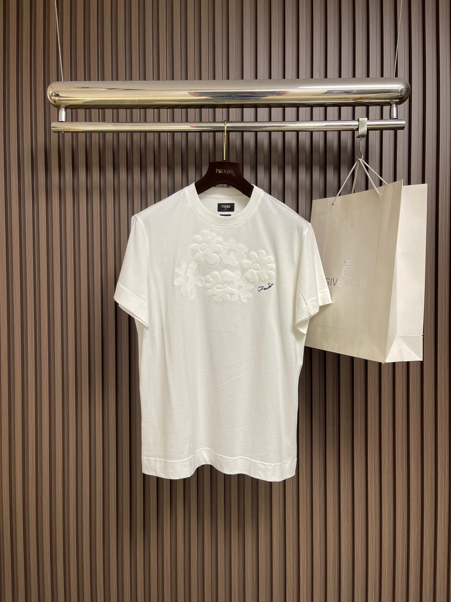 NO:848715,Fendi  The patchwork embroidered round neck short-sleeved T-shirt is made of pure cotton with a weight of 1.5g. It is derived from natural cotton fiber. It has a soft and delicate touch, is skin-friendly and non-irritating, and can be worn by sensitive skin with peace of mind. Using the 20S1 compact spinning process, the yarn has less hairiness, even slenderness, clear and regular texture, and is more visually noticeable.  Exquisite and high-end. At the same time, the natural breathable pores of cotton fiber are retained, and the moisture absorption and perspiration effect is excellent. Compared with ordinary plain cotton, the dense cotton cloth is more wear-resistant, less prone to pilling, and more durable for daily wear. The same color high-gloss embroidery thread is used, and the embroidery machine is operated with high precision, and the stitches are tightly arranged without skipping.  The phenomenon of thread and missing stitches, the edge of the logo is clear and sharp, showing a three-dimensional and full visual effect. When touching, you can feel the uniform raised texture, which is solid and layered; the embroidery area is accurately located in the center below the back collar, with coordinated proportions and no offset, skew and other problems. The flowers are decorated with blue  The polyester fiber embroidery thread embroidery forms a soft contrast with the white background. The handwritten embroidery restores the original brushstroke details, with smooth and natural lines; the embroidery stitches are fine and firm, and will not easily come off or turn white after being worn for a long time. The overall threading is straight and delicate, the fabric is comfortable and soft, and the colors are consistent without color difference.  It can be matched with the same style to create a fashionable look, and can be used in various occasions. Customized accessories, complete with three standards, same style for men and women!  Size S-XL 46-52 46 yards shoulder width 47 bust 106 length 68 48 yards shoulder width 48 chest 110 length 69.5 50 yards shoulder width 49 chest 114 length 71 52 yards shoulder width 50 chest 118 length 72.5,, fendi, T-shirt, tees, t-shirt,19860909Fendi 贴布绣花圆领短袖t恤,选用纯棉材质,克重达g,源自天然棉纤维,触感柔软细腻,亲肤不刺激,敏感肌也能安心穿着.采用20S1紧密纺工艺,纱线毛羽少、条干均匀,纹理清晰规整,视觉上更显精致高级.同时保留了棉纤维的天然透气孔,吸湿排汗效果出色相比普通平纹棉,紧密棉的布面更耐磨、不易起球,日常穿着更耐造.选用同色系高光泽绣线,通过绣花机高精度作业,针脚紧密排列无跳线、漏针现象,标志边缘清晰锐利,呈现出立体饱满的视觉效果,触摸时能感受到均匀的凸起质感,扎实且富有层次；刺绣区域精准位于后领下方中央,比例协调,无偏移、歪斜等问题.花朵旁饰以蓝色聚酯纤维绣线刺绣,与白色底色形成柔和撞色,手写体的刺绣还原了原版的笔触细节,线条流畅自然；刺绣针脚细密牢固,久穿不易脱线、不易发白.整体走线平直细腻,面料舒适柔软,颜色一致无色差 能与同款搭配营造时尚造型,驾驭各种场合,定制辅料,三标齐全,男女同款！尺码S-XL 46-52 46码 肩宽47胸围106衣长68 48码 肩宽48胸围110衣长69.5 50码 肩宽49胸围114衣长71 52码 肩宽50胸围118衣长72.5,,fendi,T-shirt,tees，t-shirt,,Men's clothing
