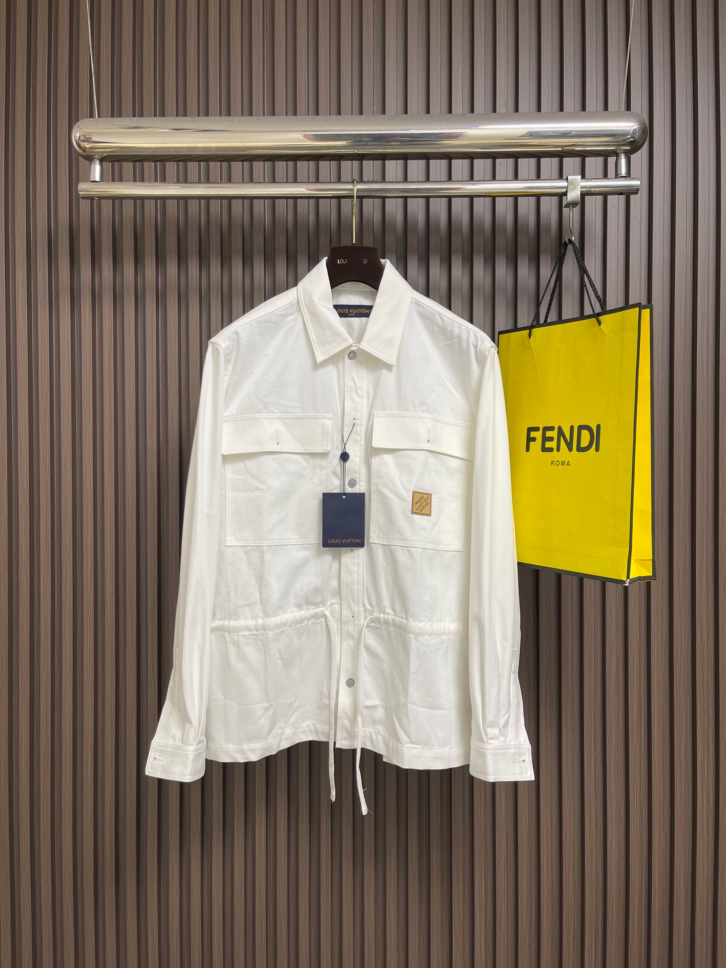 NO:856092,LV  Leather label printed shirt jacket. The fabric is made of the original heavy-weight combed cotton twill fabric. It has been pre-shrunk and anti-pilling. It feels thick and crisp, has excellent breathability, and is not easy to deform after long-term wear. The lapel adopts three-dimensional shaping technology and the edges are hand-edged.  It fits the neck line; the placket is sewn in precise position, with customized metal buttons, and the buckle is stable and delicate. The double patch pockets on the front are reinforced with double-needle crimping, and the same-color buttons on the bag flap are fixed, which combines practicality and visual layering; the waist is made of  Drawstring waist design, built-in adjustable drawstring, free to switch between loose and waisted styles. The leather brand logo is sewn on the left chest, and the details highlight the light luxury texture; the sleeves are slightly cut, the cuffs are double-needle pressed and adjustable button design, allowing free movement. Overall  The stitching is made of high-elastic thread of the same color, the stitches are fine and even, the hem is straight and neat, and the craftsmanship takes into account both practicality and high-end feel. It is custom-woven and dyed, without any color difference from the original version. The ingenious craftsmanship is perfectly restored, three standards are complete, and customized accessories are available. Sizes S-XL  Size S, bust 116, shoulder width 49.5, length 72, size M, bust 120, width 51, length 74, size L, size bust 124, width 52.5, length 76, size XL, size bust 128, width 54, length 78, Louis Vuitton, jackets & coats, shirts,19860909LV 皮标印花衬衫外套,面料采用原版一致重磅精梳棉斜纹面料,经预缩与抗起球处理,触感厚实挺括,透气性优异,久穿不易变形.翻领采用立体定型工艺,边缘手工包边,贴合颈部线条；门襟精准对位缝制,搭配定制金属纽扣,扣合稳固质感细腻.前胸双贴袋采用双针压线加固,袋盖处同色系纽扣固定,兼具实用性与视觉层次感；腰部采用抽绳收腰设计,内置可调节抽绳,自由切换宽松与收腰版型.左胸缝制皮质品牌标,细节彰显轻奢质感；袖身微收剪裁,袖口双针压线与可调节纽扣设计,活动自如.整体缝线采用同色系高弹线,针脚细密均匀,下摆平直利落,工艺兼顾实用性与高级感.定织定染,与原版无任何色差.匠心工艺完美还原,三标齐全,定制辅料.尺码S-XL S码 胸围116肩宽49.5 衣长72 M码胸围120肩宽51 衣长74 L码 胸围124肩宽52.5 衣长76 XL码胸围128肩宽54 衣长78,,louis vuitton,jackets & coats,shirts,,Men's clothing