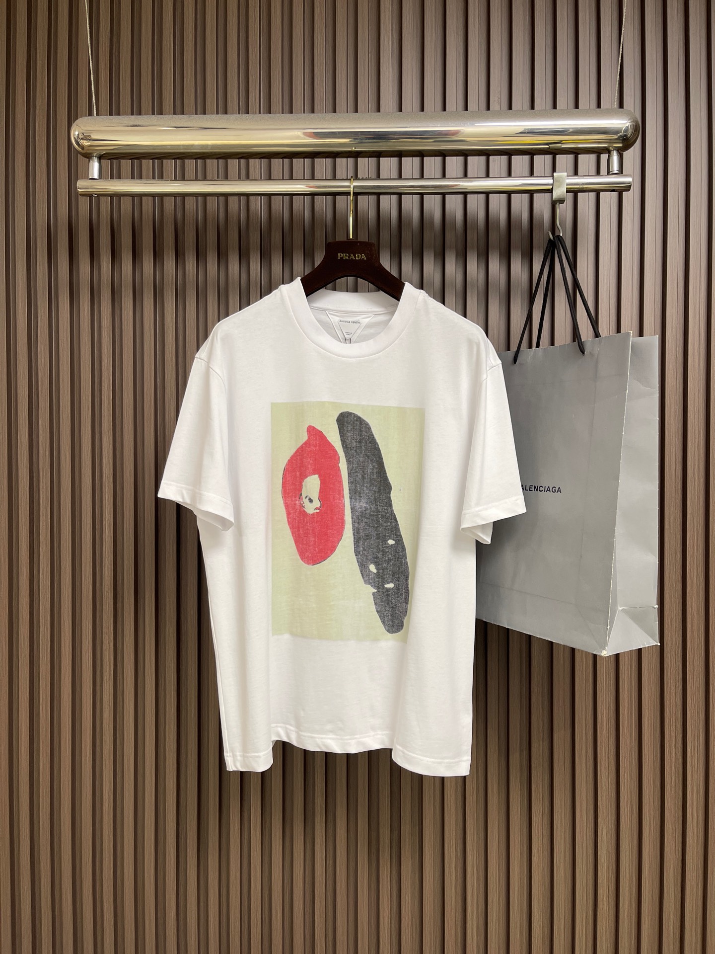 NO:856100,BV  Abstract art printed short-sleeved T-shirt, made of high-count combed double-ply pure cotton fabric. The texture of the fabric is fine and tight, soft and smooth to the touch, with both stiffness and drape. The upper body is not soft or tight, and it perfectly creates a relaxed and advanced silhouette. The high-density weaving structure allows the clothing to be breathable and sweat-wicking, making it dry and not stuffy to wear in summer.  It is sweat-resistant, wrinkle-resistant and easy to care for, not easy to pill when worn for a long time, washable and durable, taking into account comfort and high-end texture. The front of the body adopts a double-layer composite printing process, and the core base is full-width digital printing. The blue abstract color block and black background are sprayed through high-precision digital direct printing, with natural color transitions, accurate pattern restoration, and detailed details.  The texture is clear and the texture of perfect abstract artistic strokes. Because white digital printing is done directly on the black base fabric, it cannot show the ultimate bright white effect due to the background color. The brand added a manual screen printing process to superimpose the white pattern a second time and manually position the overprint to make the white printing layer fuller and the color more solid, perfect.  Balances artistic sense and color saturation, the printing is firm and not easy to crack or fall off, and it remains refined and stylish for long-term wear. The underside of the back collar uses inverted triangle precision embroidery routing. The triangular structure reinforces the collar to prevent loosening and deformation after long-term wear. The routing is neat and neat, the stitching is fine and even, and the texture is low-key and hidden. Sizes S-XL  Size S, shoulder width 51, bust 114, length 70.5, size M, shoulder width 52, bust 118, length 72, size L, shoulder width 53, bust 122, length 73.5, size XL, shoulder width 54, bust 126, length 75,,bottega veneta,T-shirt,tees,t-shirt,19860909BV 抽象艺术印花短袖T恤,选用高支精梳双股纯棉面料,面料肌理细腻紧实,触感软糯顺滑,兼具挺括度与垂坠感,上身不软塌、不紧绷,完美塑造松弛高级的版型轮廓.高密度织造结构让衣物透气排汗,夏日穿着干爽不闷汗,同时抗皱易打理,久穿不易起球,耐洗耐穿,兼顾舒适度与高级质感.衣身正面采用双层复合印花工艺,核心基底为全幅数码印花,蓝色抽象色块与黑色底色通过高精度数码直喷,色彩过渡自然,图案还原度精准,细节纹理清晰,完美抽象艺术笔触的肌理质感,因黑色底布上直接做白色数码印花,受底色影响无法呈现极致亮白效果,品牌追加手工丝网印工艺二次叠加白色图案,人工定位套印,让白色印花层次更饱满、色彩更扎实,完美平衡艺术感与色彩饱和度,印花牢固不易开裂、脱落,长期穿着依旧精致有型,后领下方采用倒三角精密绣花走线,三角结构加固领口,防止久穿松垮变形,走线工整利落,针脚细腻均匀,低调暗藏细节质感.尺码S-XL  S码 肩宽51 胸围114 衣长70.5 M码肩宽52 胸围118 衣长72 L码 肩宽53 胸围122 衣长73.5 XL码 肩宽54 胸围126 衣长75,,bottega veneta,T-shirt,tees，t-shirt,,Men's clothing