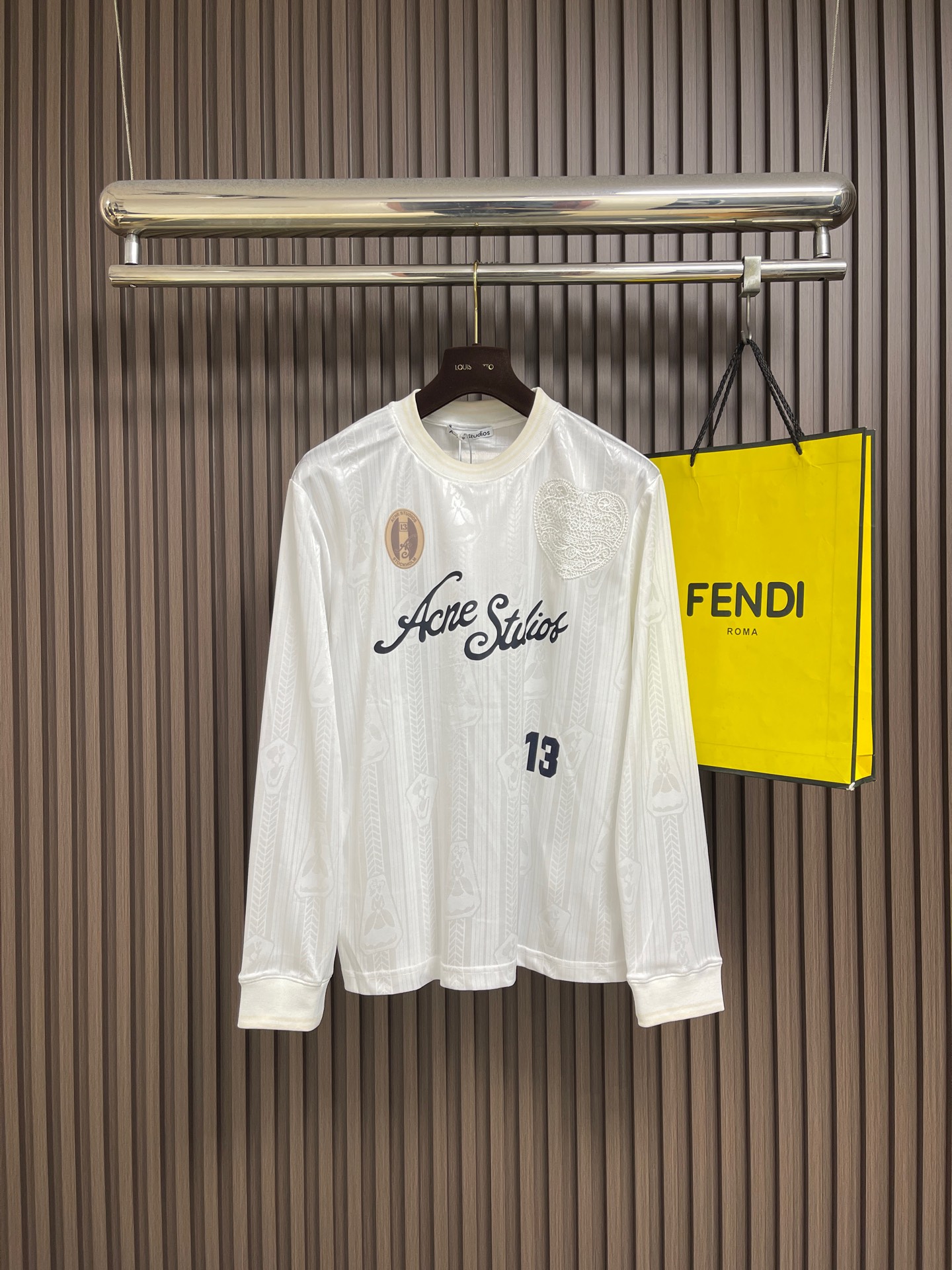 NO:911602,Acne Studios football jersey technical jacquard fabric logo long-sleeved T-shirt, this Acne  The Studios logo long-sleeved top is woven from an exclusive technical jacquard fabric. The fabric body has a delicate dark texture, which is smooth, light, breathable and skin-friendly. It has a drapey feel and comfortable elasticity, making it non-restrictive for daily wear. The body is decorated with a combination of multiple techniques.  , the handwritten brand letters on the front adopt precision offset printing technology, with clear lines and not easy to crack and fall off. The side digital printing, chest badge patch and heart jacquard are rich in layers. The edge of the patch is neatly overlocked and strong and washable. The back is spliced with contrasting cloth labels and three-dimensional letter printing.  The flower is flat and plump, the round neck is matched with rib cuffs of the same fabric, the elasticity is long-lasting and not easy to loosen, and the cuffs are delicately hemmed. The whole piece of clothing is made of double-thread flat stitching, the stitching is even and dense, and the seams are regular. The cut is loose and the dropped shoulders are suitable for a variety of body shapes. The whole piece is made of  Mild printing and dyeing process is used to fix the color, which is not easy to fade. It is recommended to hand wash gently for care. The slight measurement error of 1-3cm is within the scope of normal craftsmanship. It has both trendy appearance and solid garment workmanship. The overall wiring is straight and delicate, the fabric is comfortable and soft, and the color is consistent without color difference.  Can be matched with the same style to create a fashionable look, to suit various occasions, customized accessories, complete with three standards!  Size S-XL S size bust 110 shoulder width 46.6 length 70 medium size bust 114 shoulder width 47.8 length 71.5 L size bust 118 shoulder width 49 length 73 XL size bust 123 shoulder width 50.2 length 74.5,,acne studios,dior,tees,t-shirt,19860909Acne Studios 足球服科技提花面料徽标长袖T恤,这款Acne Studios徽标长袖上衣甄选专属科技提花面料织造,布身自带细腻暗纹肌理,触感顺滑轻薄且透气亲肤,兼顾垂坠感与舒适弹力,日常穿着无束缚感.衣身采用多工艺组合装饰,正面手写体品牌字母采用精密胶印工艺,线条清晰不易开裂脱落,侧边数字印花、胸口徽章贴片与爱心提花层次丰富,贴片边缘工整锁边牢固耐洗.后背拼接撞色布标,立体字母印花平整饱满,圆领搭配同面料罗纹收口,弹力持久不易松垮,袖口做细腻包边处理.整件衣物采用双线平缝车工,走线均匀密实,锁边规整,剪裁宽松落肩版型包容多种身形,全件采用温和印染固色工艺,不易褪色,洗护建议轻柔手洗,细微1-3cm测量误差属于正常工艺范畴,兼具潮流外观与扎实成衣做工.整体走线平直细腻,面料舒适柔软,颜色一致无色差 能与同款搭配营造时尚造型,驾驭各种场合,定制辅料,三标齐全！尺码S-XL S码胸围110 肩宽46.6 衣长70 M码 胸围114 肩宽47.8衣长71.5 L码胸围118 肩宽49衣长73 XL码 胸围123 肩宽50.2 衣长74.5,,acne studios,dior,tees，t-shirt,,Men's clothing