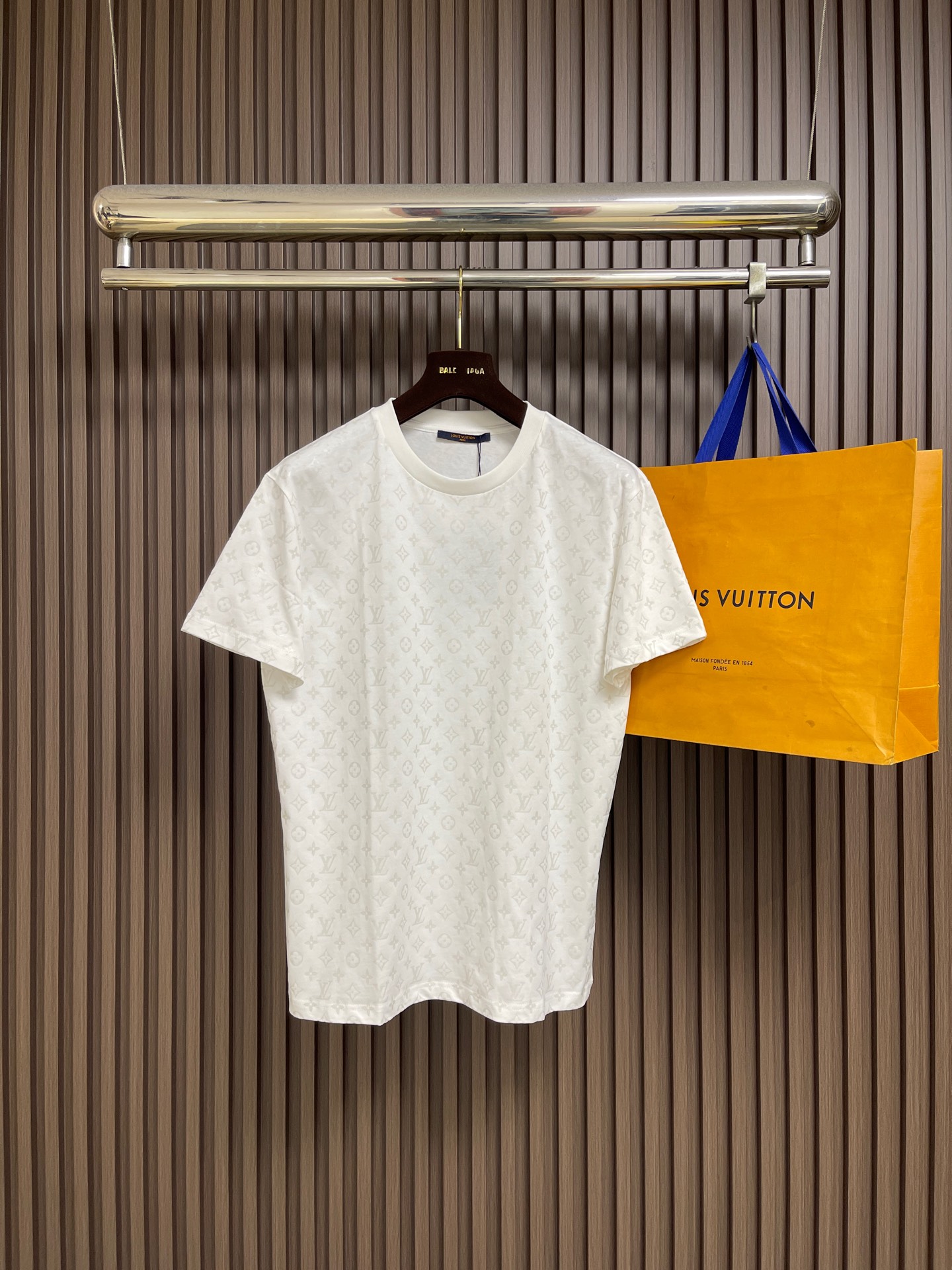 NO:928727,LV  Firefly printed round neck short-sleeved T-shirt is made of 15S special-spun compact cotton with a weight of 230gm. It is matched with 32S1×1 ribbing on the neck and has a weight of up to 340gm. Compact spinning technology can effectively eliminate yarn hairiness, make the yarn body smooth and even, which makes the surface of the fabric appear...  It shows a high-end texture with a slightly matte surface and improves the anti-pilling performance. The fabric is medium-weight and has a drapey feel and a flexible frame. It can naturally fit the body curves and maintain the contour. This high-density, high-weight rib has a tight structure, solid texture, and excellent elasticity and rebound.  It is elastic and can firmly lock the collar. This is the core process of the entire T-shirt. A special paste is printed on the fabric through screen printing. This paste can absorb and reflect light energy when exposed to ultraviolet light, highlighting the unique color of the pattern. Under normal light, the pattern appears  Now it has a same-color effect with consistent tones; when placed in the dark and irradiated by ultraviolet light, the printing energy will be slowly released in the form of shimmer, making the Monogram pattern clearly appear. This process requires the printing slurry to be evenly adhered, and the luminous powder needs to be stable in the slurry  Distribution to ensure long-lasting and uniform luminous effect. The key to ensuring visual uniformity of the all-over pattern. This means that every piece from the body, sleeves to side seams must be strictly aligned with the printed pattern when cutting and sewing. The position of each piece needs to be accurately calculated when laying out;  Single piece cutting is used to ensure accuracy; when sewing, the sewing worker needs to constantly adjust during the sewing process to ensure that the patterns at the shoulder seams, side seams and other splicing areas can be seamlessly connected and the lines run through. Using a standard version design, the shoulder line accurately falls on the acromion point, outlining a clear shoulder outline; the body  It has a straight cut, with similar bust and hem circumferences. It fits well but is not tight, leaving a moderate amount of room for movement. The sleeves are standard short sleeve length, and the cuffs and hem are finely cuffed. The structure is simple and neat. The overall version is neither too loose nor too narrow, providing a perfect fit for the all-over presbyopia pattern.  The flat and complete display area allows the pattern to be evenly laid out on the chest, back and sleeves to avoid excessive deformation of the pattern that may affect the visual effect of the printing, while ensuring the comfort and versatility of daily wear. The overall routing is straight and delicate, the fabric is comfortable and soft, and the colors are consistent and without color difference.  Can be matched with the same style to create a fashionable look, to suit various occasions, customized accessories, complete with three standards!  Size SML19860909LV 荧火虫印花圆领短袖T恤,选用15S特纺紧密棉,克重为230gm；搭配领口32S1×1罗纹,克重高达340gm.紧密纺技术能有效消除纱线毛羽,使纱体光洁、条干均匀,这让面料表面呈现出微雾面的高级质感,并提升了抗起毛球性能.面料中克重,兼具了垂坠感与柔韧的骨架；能自然地贴合身体曲线,保持轮廓.这种高密度、高克重的罗纹结构紧密、质地扎实,具有极佳的弹力和回弹性,能牢牢锁住领圈.这是整件T恤最核心的工艺,通过丝网印刷将含有特殊浆料印制在面料上.这种浆料在紫外光照射时能吸收并光能进行反射作用,凸显出图案独有色彩.在正常光线下,图案呈现为色调一致的同色系效果；当置于黑暗中经紫外线灯照射时,印花的能量便会以微光的形式缓慢释放,使Monogram图案清晰显现.该工艺要求印花浆料能均匀附着,且夜光粉需在浆料中稳定分布,以确保发光效果持久均匀.确保通体图案视觉统一的关键.这意味着从大身、袖子到侧缝的每一片裁片,在裁剪和缝制时都必须严格对齐印花图案.排料时需精确计算每片裁片的位置；裁剪时多采用单片裁剪以保证精度；缝制时,缝纫工需在车缝过程中不断调整,确保肩缝、侧缝等拼接处的图案能无缝连接、纹路贯通.采用标准版型设计,肩线精准落在肩峰点,勾勒出清晰的肩部轮廓；衣身呈直筒剪裁,胸围与下摆围度相近,合身而不紧身,留有适度活动空间.袖型为标准短袖长度,袖口与下摆均采用精细收口,结构简洁利落.整体版型不过分宽松也不过分收窄,为通体老花图案提供了平整完整的展示区域,图案得以均匀铺陈于前胸、后背及袖面,避免因版型过度变形而影响印花视觉效果,同时确保日常穿着的舒适性与搭配普适性.整体走线平直细腻,面料舒适柔软,颜色一致无色差 能与同款搭配营造时尚造型,驾驭各种场合,定制辅料,三标齐全！尺码SMLXL S码 衣长68　 胸围108　 肩宽38 M码 衣长70　 胸围112　 肩宽40 L码 衣长72　 胸围116　 肩宽42 XL码衣长74　 胸围120　 肩宽44,,louis vuitton,T-shirt,tees，t-shirt,,Men's clothing