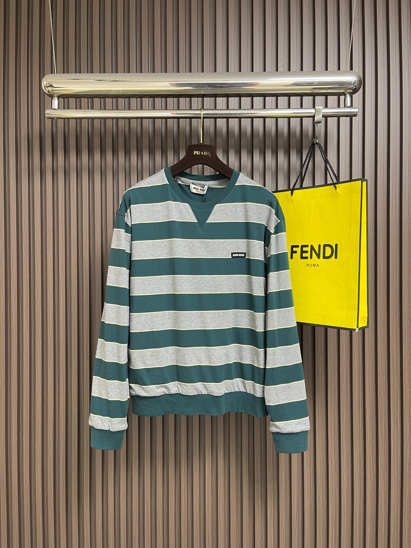 NO:928830,MIU MIU color block striped double layer sweatshirt  , the cutting process of this sweatshirt is considered to be the most difficult in the industry. It completely breaks the conventional single-layer cutting logic and adopts the simultaneous cutting process of double-layer fabrics. The process is cumbersome and requires extremely high precision. The outer layer is made of high-count fine cotton blended fabric, and the inner layer is  Equipped with a soft, waxy, skin-friendly and breathable layer, the two-layer fabrics have completely different textures, tensions and textures. Before cutting, they need to undergo multiple pre-processings of constant temperature pre-shrinking, static elimination, and flatness calibration to prevent subsequent deformation and layer shifting. The cutting machine adopts multi-version type separation.  In the piece disassembly mode, more than ten pieces such as the body, sleeves, neckline, and splicing positions are positioned independently. The entire process relies on laser positioning and calibration. It is necessary to simultaneously control the cutting angle, edge flatness and pattern fit of the double-layer fabric, as well as the size error of the pieces.  Strictly controlled within 0.1mm, the material consumption rate and process time are far higher than ordinary sweaters. Every cutting step requires double verification by manual and machine, and the cutting bed is extremely complex. The overall wiring is straight and delicate, the fabric is comfortable and soft, and the color is consistent without color difference.  It can be matched with the same style to create a fashionable look, and can be used in various occasions. Customized accessories, complete with three standards, same style for men and women!  Size SMLXL,,miumiu,hoodie,sweatshirts,19860909MIU MIU拼色条纹双层卫衣 ,这款卫衣的裁床工序堪称行业高阶难度,彻底打破常规单层裁片逻辑,采用双层面料同步裁切工艺,工序繁琐且精度要求极高.外层精选高支精棉混纺面料,内层搭配软糯亲肤透气层,双层面料质感、张力、纹路全然不同,裁切前需经过恒温预缩、静电消除、平整度校准多重预处理,杜绝后续形变与层间移位.裁床采用多版型分片拆解模式,衣身、袖身、领口、拼接位等十余块裁片独立定位,全程依托激光定位校准,需同步把控双层面料的裁切角度、边缘平整度与版型契合度,裁片尺寸误差严控在0.1mm内,耗料率与工艺耗时远超普通卫衣,每一步裁切都需人工与机器双重核验,裁床复杂度拉满.整体走线平直细腻,面料舒适柔软,颜色一致无色差 能与同款搭配营造时尚造型,驾驭各种场合,定制辅料,三标齐全,男女同款！ 尺码SMLXL,,miumiu,hoodie,sweatshirts,,Men's clothing