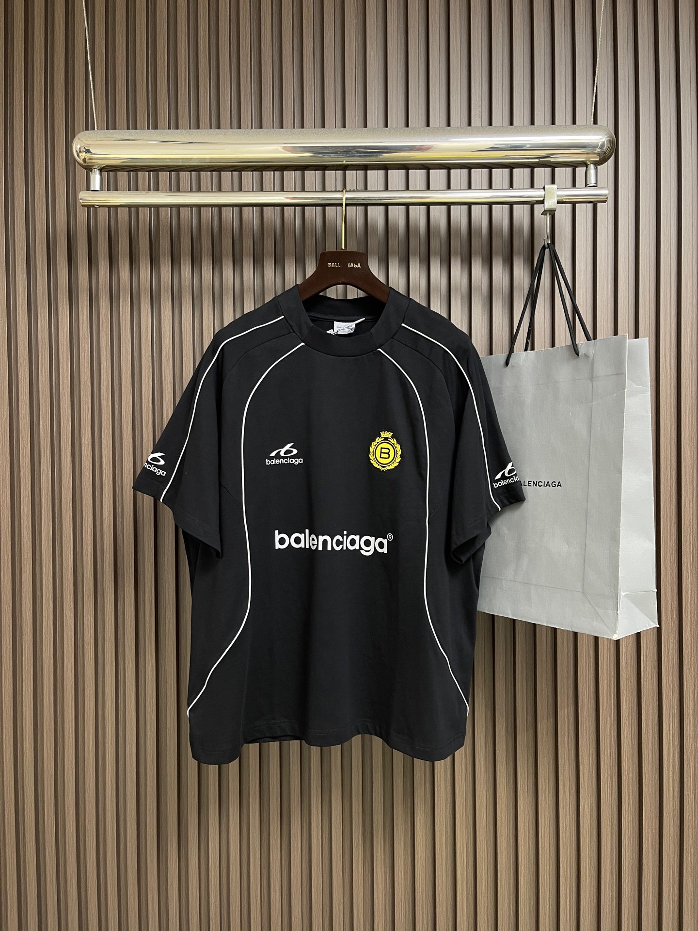 NO:945792,Balenciaga  Manchester United football co-branded short-sleeved T-shirt, this Balenciaga sports-style short-sleeved T-shirt is made of high-count combed cotton fabric, which is soft and breathable to the touch, comfortable and skin-friendly. The overall design adopts a loose off-shoulder version, with neat and casual lines, and has a relaxed street atmosphere. The body is mainly black, with a white top-line curved edge design, which outlines the classic outline of a sports jersey and restores a retro competitive feel. There is a clear brand letter logo printed on the chest.  The logo and sports style logo are paired with the yellow badge embroidery on the left chest. The embroidery stitches are fine and flat, with bright colors and high-end texture. The neckline adopts reinforced rib technology, which is not easy to deform after long-term wear. The overall workmanship is rigorous, and the wiring is neat and firm. It cleverly combines retro sports aesthetics with the brand's pioneering style. It has both trend recognition and daily practicality, and can easily create a personalized street style. The overall wiring is straight and delicate, the fabric is comfortable and soft, and the colors are consistent and without color difference.  Can be matched with the same style to create a fashionable look, to suit various occasions, customized accessories, complete with three standards!  Size XS-S-M-L19860909Balenciaga 曼联足球联名短袖T恤,这款Balenciaga运动风短袖T恤,甄选高支精梳棉面料打造,触感柔软透气,穿着舒适亲肤.整体采用宽松落肩版型,线条利落随性,自带松弛街头氛围.衣身以黑色为主调,搭配白色明线弧形包边设计,勾勒出运动球衣的经典轮廓,还原复古竞技感.胸前印有清晰的品牌字母标识与运动风logo,搭配左胸黄色徽章刺绣,刺绣针脚细密平整,色彩鲜明,质感高级.领口采用加固罗纹工艺,久穿不易变形,整体做工严谨,走线工整牢固,将复古运动美学与品牌先锋风格巧妙融合,兼具潮流辨识度与日常实穿性,轻松打造个性街头造型.整体走线平直细腻,面料舒适柔软,颜色一致无色差 能与同款搭配营造时尚造型,驾驭各种场合,定制辅料,三标齐全！尺码XS-S-M-L XS码衣长71.5 胸围126 袖长38.8 S码 衣长73胸围130 袖长40 M码 衣长74.5 胸围134 袖长41.2 L码 衣长76胸围138袖长42.4,,balenciaga,T-shirt,tees，t-shirt,,Men's clothing