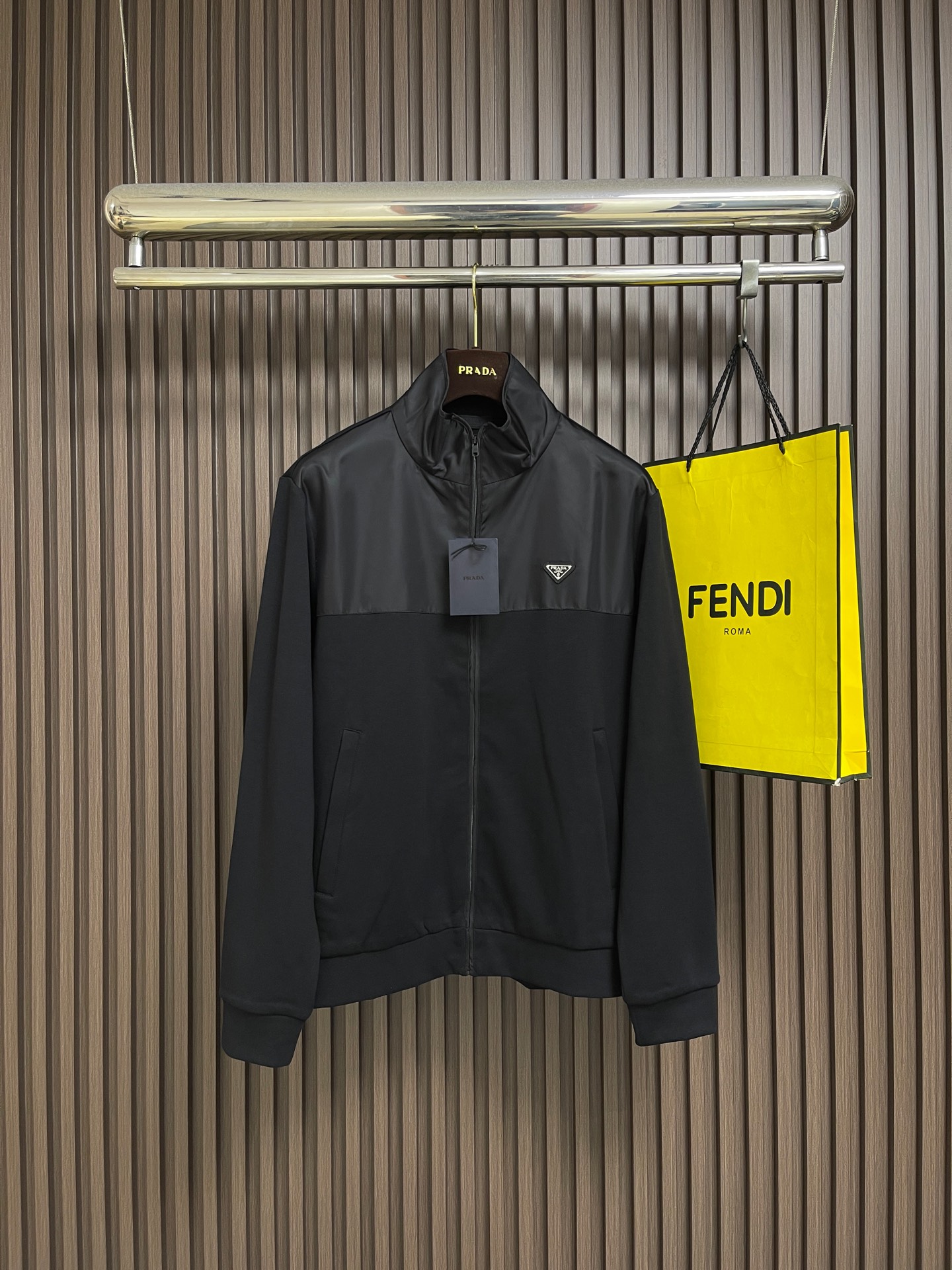 NO:950735,Prada  The cotton spliced nylon jacket is made of two-material segmented splicing. The stand-up collar and placket areas are made of high-density nylon fabric, and the body, sleeves, hem, etc. are made of cotton knitted fabric. The nylon surface layer is made of high-density plain weave technology, and the cloth surface has a fine matte luster. The yarn is tight and tear-resistant, and is resistant to dirt and easy to wipe. It is stiff and not easy to wrinkle after being shaped, and it remains flat for a long time.  type; the cotton knitted main body is woven with high-elastic cotton blended yarn. The fine knitted texture is soft and skin-friendly, with sufficient breathable pores. It can wick away sweat during daily activities without stuffing the body. It has a soft drape feeling, moderate elasticity and is not tight. (Both fabrics are pre-shrunk, fixed and washed, and the shrinkage rate is uniform at the splicing. Long-term wear will not cause length misalignment, whitening and fading problems)  The pieces are pre-divided and cut using the segmented alignment splicing process. The nylon panels on the neckline and front chest are accurately aligned with the cotton body. Double-layer overlock seams are used at the splicing points. The outer layer is evenly reinforced with double open stitches. The stitch length is uniform and regular, which disperses the pulling force at the splicing area and greatly reduces the risk.  There are no problems with thread breakage and layering when worn and washed. There are no burrs inside or outside, and the splicing lines are smooth and smooth. The one-piece stand-up collar is sewn with double-layer nylon panels. The collar is shaped with multiple parallel topstitch lines, which is not easy to collapse and roll. The middle is a customized metal nylon full-width zipper with die-cast words on the zipper head.  Mother logo, teeth bite smoothly without jamming, double-layer fabric wrapping and reinforcement on both sides of the zipper, it is not easy to collapse after repeated pulling, and the zipper track is straight and neat. Zipper pockets are inserted diagonally on both sides, the bag is double-layered with composite lock stitching, with invisible zippers of the same color, and full line reinforcement around the bag mouth.  It is not easy to deform and crack when pulled. The cuffs and hem are made of high-elastic cotton rib knitting of the same color, double-layered and sewn in half. The elasticity is long-lasting and not easy to loosen and deform. It fits the wrists and is not tight on the waist and abdomen. It is windproof and temperature-locking during exercise. The bends are wear-resistant and anti-pilling, and the edges will not loosen after repeated washing.  Size S-XL Size S, length 68, bust 116, shoulder width 47, sleeve length 64, size M, length 69.5, bust 120, shoulder width 48, sleeve length 65, size L, length 71, bust 124, shoulder width 49, length of sleeves 66, size XL, length 72.5, bust 128, shoulder width 50, sleeve length 67,19860909Prada 棉质拼接尼龙外套,采用双材质分段拼接,立领、门襟区域为高密尼龙面料,衣身、袖子、下摆等选用棉质针织面料.尼龙面层采用高密平纹梭织工艺,布面自带细腻哑光光泽,纱线紧实抗撕裂,且耐脏易擦拭,定型后挺括不易起皱,长久穿着保持平整版型；棉质针织主体选用高弹棉混纺纱线织造,细密针织肌理柔软亲肤,透气孔隙充足,日常活动排汗不闷身,自带柔和垂坠感,弹力适中不紧绷.(两种面料均经过预缩、固色水洗后整理,拼接处收缩率统一,长期穿着不会出现长短错位、发白掉色问题) 分段对位拼接工艺裁片预先分区分料裁剪,领口、前胸尼龙裁片与棉质衣身精准对位,拼接处采用双层包缝锁边,外层双道明线均匀加固,针距统一规整,分散拼接处拉扯受力,大幅度降低穿洗断线、分层起翘问题,里外无毛边毛刺,拼接线条流畅平整.一体式立领采用双层尼龙裁片复合缝制,领口多道平行明线定型,不易软塌翻卷；中间定制金属尼龙全幅拉链,拉链头压铸字母标识,齿牙咬合顺滑不卡顿,拉链两侧双层布料包边加固,反复拉合不易崩线,拉链轨道走线平直工整.两侧斜插拉链口袋,袋片双层复合锁缝,搭配同色系隐形拉链,袋口四周满线加固,拉扯不易变形开裂.袖口、下摆采用高弹同色系棉质罗纹针织,双层对折车缝,弹力持久不易松弛变形,贴合手腕、腰腹不紧绷,运动时防风锁温,弯折处耐磨抗起球,多次洗涤不松垮卷边. 尺码S-XL S码衣长68胸围116 肩宽47 袖长64 M码 衣长69.5胸围120 肩宽48 袖长65 L码衣长71胸围124 肩宽49 袖长66 XL码 衣长72.5胸围128 肩宽50 袖长67,,prada,jackets & coats,,Men's clothing