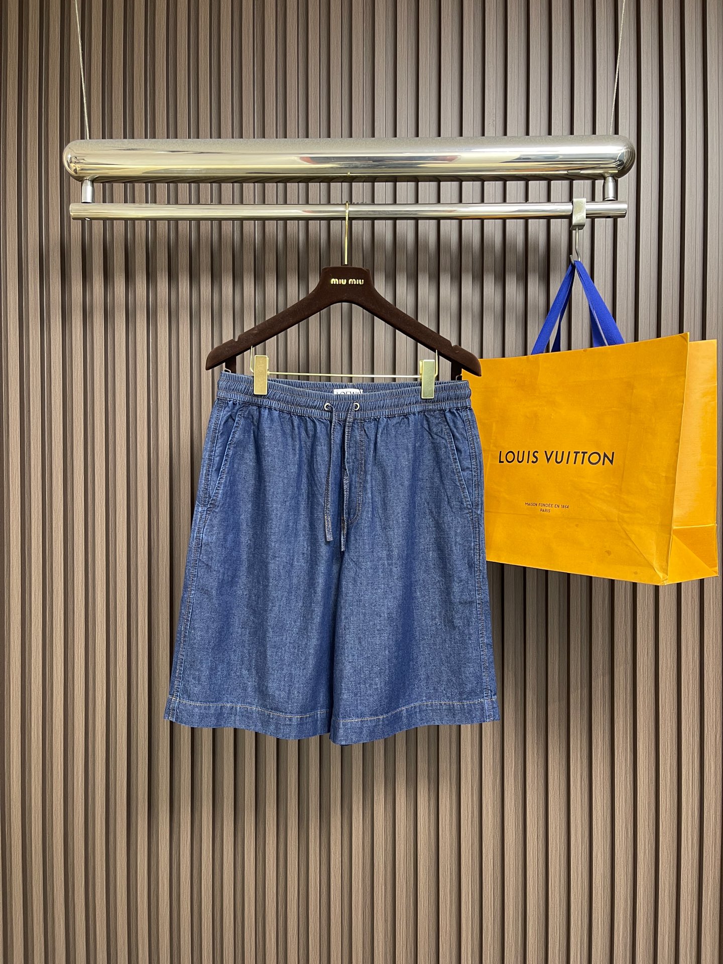 NO:950714,Tops shorts P Loewe  Patch pocket embroidered denim jacket and denim shorts set is made of lightweight cotton chambray denim fabric, made with plain weave and close weaving technology. The warp and weft cotton yarns are evenly interwoven, and the fabric surface presents a delicate and clear denim grain texture. It feels soft and thin, and has a moderate drape. It is stiff and not easy to wrinkle and deform. The gray fabric has been washed, pre-shrunk and softened to remove the hard pulpy feel of the fabric, making the upper body light and pressure-free, breathable and breathable.  Sweat-free. The Anagram pattern is created using exclusive appliqué technology. First, the cut-out denim pattern pieces are accurately positioned on the patch bag base, and fixed on the positioning frame of the embroidery machine to prevent deviation. The needle is double-layered and densely embroidered to lock the fabric piece along the outer contour of the pattern, and the special raw edge embroidery stitch method is simultaneously used to outline the edge. The embroidery threads are staggered and stacked to create a fluffy three-dimensional fringe texture, and the multi-layer lock embroidery structure  The patch is firmly fixed, and it is not easy to warp and fall off. The tassel texture is full and three-dimensional. The lines are clean and neat after hand-finishing. It has both three-dimensional visual texture and solid firmness. Classic lapel structure, double-layer panel seaming reinforcement at the collar, double topstitch lock stitching on the inside of the collar, which is not easy to roll up and deform. The embroidered patch pocket on the chest is paired with oblique side pockets on both sides. All pockets are reinforced with double topstitching, and the stitches are tightened at the corners.  The lock knot prevents cracking and deformation when objects are pulled daily, and the diagonal pocket fits the body, taking into account both beauty and practicality. The hem has a built-in cotton drawstring of the same material, which is fixed with metal air eyes, and the tightness of the hem can be adjusted freely; the cuffs are double-layered and hemmed with double sewing threads, and the seams are dense and washable, so there will be no problems with thread breakage or fabric tearing. Sizes S-XL, loewe, shorts, jackets  & coats,19860909上衣 短裤P Loewe 贴袋绣花牛仔外套牛仔短裤套装,选用轻盈棉质青年布牛仔面料,采用平纹紧密梭织工艺打造,经纬棉纱均匀交织,布面呈现细腻清晰的牛仔颗粒肌理,触感柔软轻薄,同时其自带适度垂坠感,挺括不易起皱变形.坯布经水洗预缩软化处理,去除布料硬性浆感,上身轻盈无压,透气排汗不闷肤.采用专属贴布绣工艺打造Anagram纹样,先将裁剪成型的牛仔布图案裁片精准对位铺置在贴袋基底上,固定于绣花机定位框防止走位偏移.针头沿图案外轮廓双层密绣锁固布片,同步运用特殊毛边绣针法勾勒边缘,绣线交错堆叠塑造蓬松立体的流苏肌理,多层锁绣结构牢牢固定贴布,不易翘边脱片,流苏纹理层次饱满立体,手工精修后线条干净利落,兼具立体视觉质感与扎实的牢固度.经典翻领结构,领部双层裁片锁边加固,领口内侧双道明线锁缝,不易翻卷变形.胸前绣花贴袋搭配两侧斜插侧袋,所有袋口全部采用双道明线加固,转角位置收针锁结,日常放置物件拉扯不易开裂变形,斜插袋贴合衣身,兼顾美观与实用性.衣摆内置棉质同料抽绳,搭配金属气眼固定,可自由调节下摆松紧；袖口双层折边双车线缝制,锁边密实耐洗,不会出现断线、布料撕裂问题.尺码S-XL,,loewe,shorts,jackets & coats,,Men's clothing