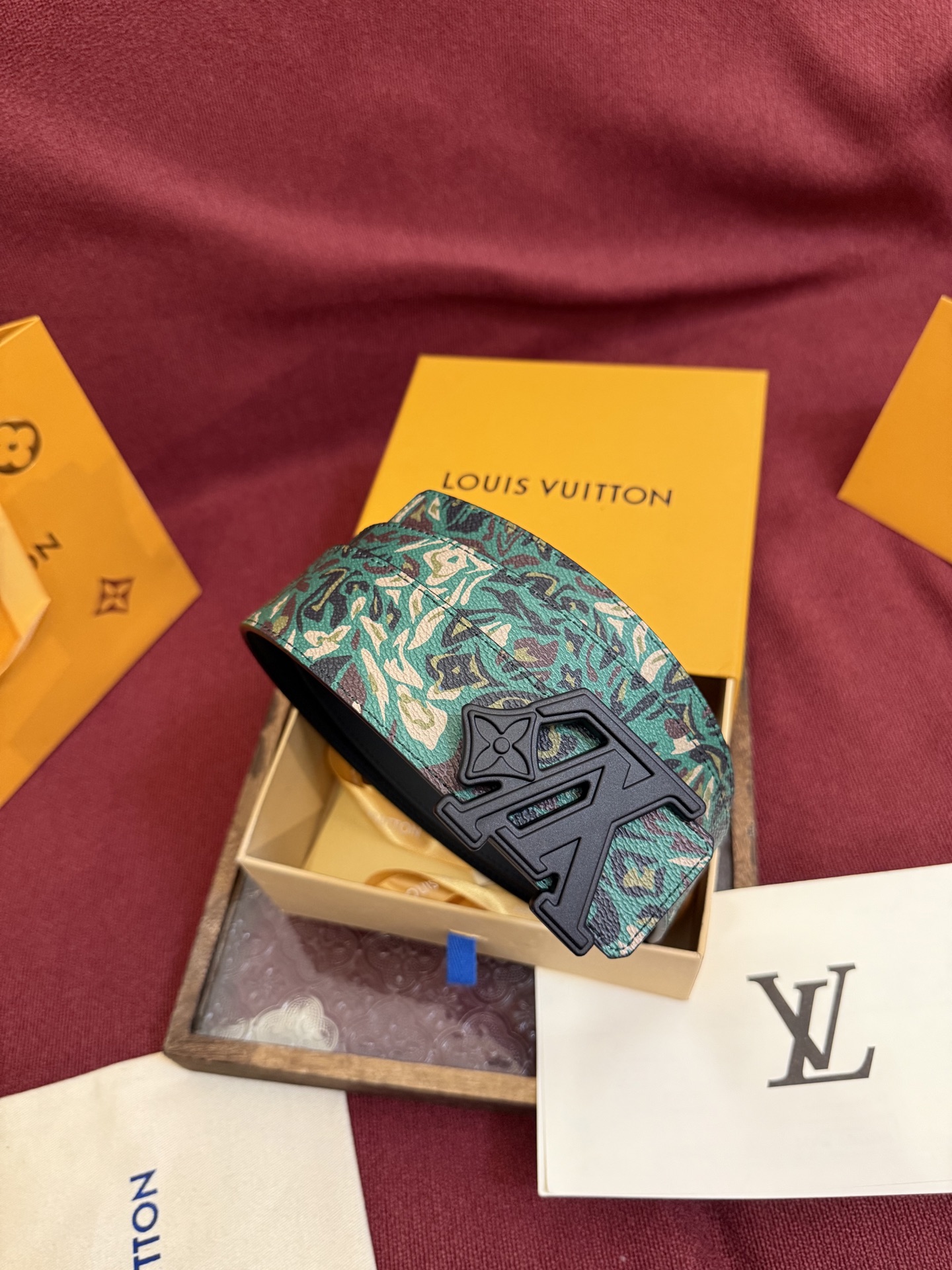 LV花卉迷彩40mm可翻转腰带是对户外爱好者长期青睐的男性主题的一次巧妙重新诠释。柔和的色调被转化为漩涡形状与品牌标识的融合。作为一款时尚优雅的替代品，反面的材质则是黑色皮革。带有花卉标识的银色扣子既适合前卫时尚的选择，也完全契合整体风格。P160