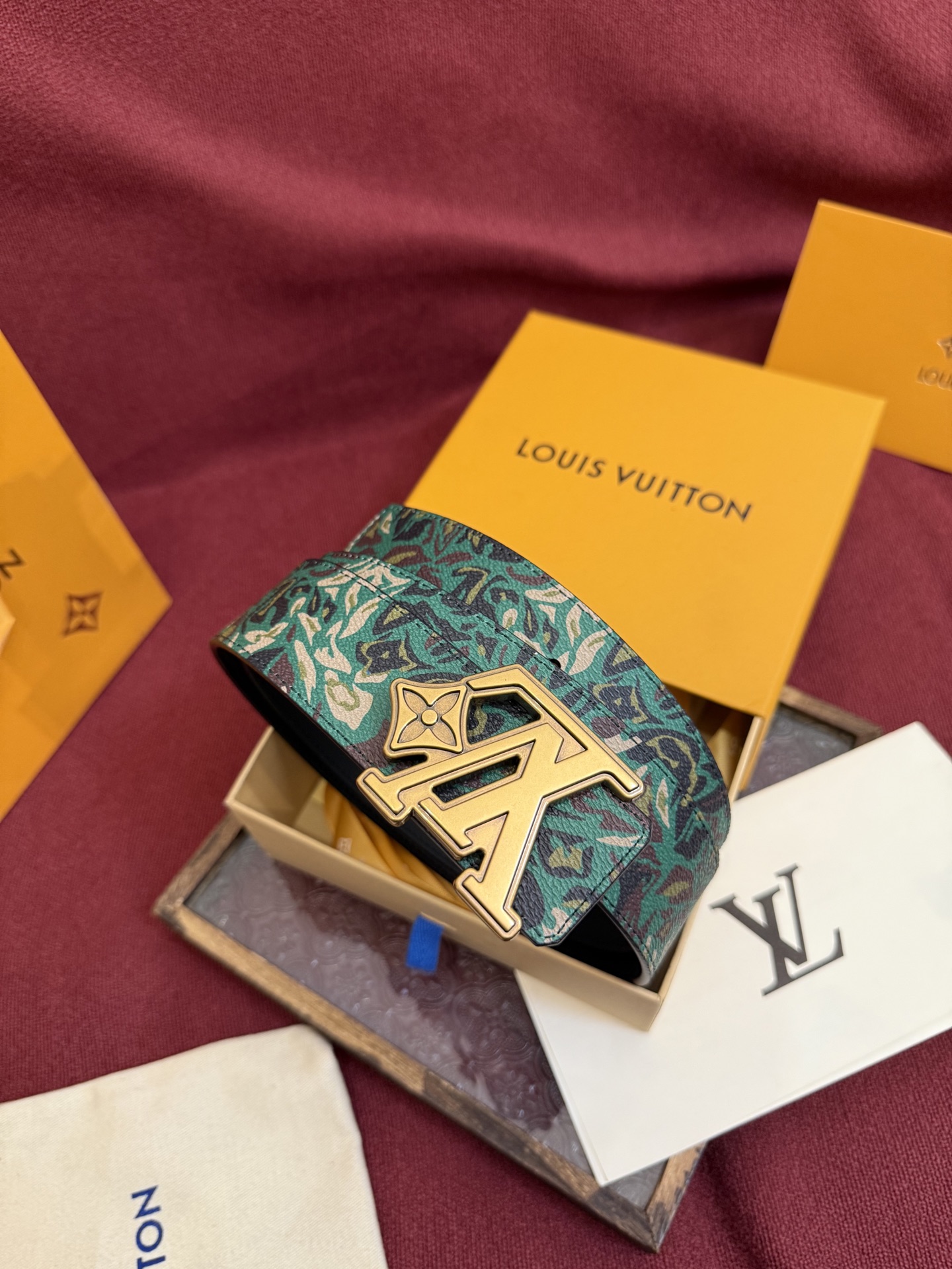 LV花卉迷彩40mm可翻转腰带是对户外爱好者长期青睐的男性主题的一次巧妙重新诠释。柔和的色调被转化为漩涡形状与品牌标识的融合。作为一款时尚优雅的替代品，反面的材质则是黑色皮革。带有花卉标识的银色扣子既适合前卫时尚的选择，也完全契合整体风格。P160