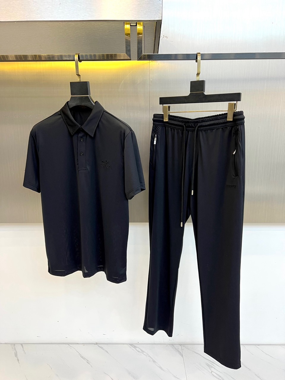 NO:945361,The new H Hermès quick-drying suit and a set of 26 spring and summer men's casual suits are newly launched, reshaping the aesthetics of daily wear with a minimalist and high-end feel. The colors are soft and elegant, with a low-key texture and a fresh spring and summer atmosphere, easily adaptable to multiple scenarios such as commuting, vacation, light socializing, etc. The top is a short-sleeved Polo shirt with a classic lapel with three buttons and a delicate HERM on the left chest.  The ES embroidered logo is concise yet revealing the brand's recognition; the bottoms are casual trousers with waistband of the same color, elastic waistband and drawstring design, side zipper pockets are practical and functional, and the trouser legs are slightly slimmed down, making you look casual and neat when walking. The whole set is made of Italian combed cotton fabric, which is soft and skin-friendly, breathable and moisture-absorbent, and the label is clearly marked 'PRODOTTO'  IN  ITALIA' and multi-lingual washing instructions, demonstrating the rigor of Italian craftsmanship and commitment to quality. The tailoring is loose and non-sloppy, tolerant, and takes into account both comfort and style. It is an ideal choice for urban men who pursue texture and relaxation. Whether it is worn with white shoes for a refreshing daily life, or with loafers for light business occasions, it can be done with ease.  In the spring and summer of 2026, let simplicity become your style and comfort blend with respectability. This set of HERMES-style casual suits will start a light and comfortable fashion journey for you. M-4XL (model weighs 173,143 pounds, upper body size L), hermes, hermes, loafers, T-shirt,19860909新品H爱马仕速干套装、一套26春夏男士休闲套装全新登场,以极简高级感重塑日常穿搭美学.色调柔和雅致,兼具低调质感与春夏清新气息,轻松适配通勤、度假、轻社交等多重场景.上衣为短袖Polo衫,经典翻领配三颗纽扣,左胸饰有精致HERMES刺绣徽标,简练中透出品牌辨识度；下装为同色系束腰休闲长裤,松紧腰头配抽绳设计,侧边拉链口袋实用又具机能美感,裤腿微收显瘦,行走间尽显随性利落.整套采用意大利产精梳棉面料,触感柔软亲肤,透气吸湿,标签清晰标注“PRODOTTO IN ITALIA”及多语洗涤说明,彰显意式工艺严谨与品质承诺.剪裁宽松不拖沓,包容性强,兼顾舒适与型格,是追求质感与松弛感的都市男士的理想之选.无论是搭配小白鞋打造清爽日常,还是配以乐福鞋出席轻商务场合,皆能从容驾驭.26春夏,让简约成为风格,让舒适融入体面,这套HERMES风休闲套装,为你开启轻盈自在的时尚旅程.M-4XL（模特173,143斤上身L码）,,hermes,hermes,loafers,T-shirt,,Men's clothing