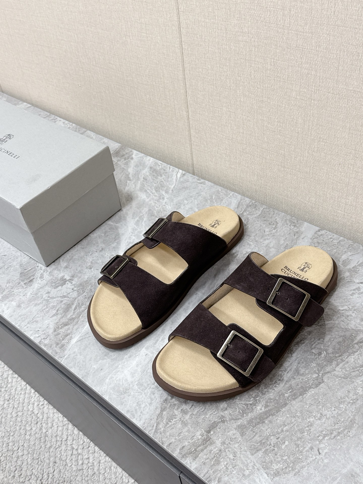 NO:851302,Brunello Cucinelli double-button suede old-money style slippers. There are many celebrity Internet celebrities. Simple and retro 'Birkenstock style' style. The color scheme is mainly earth tones (dark brown, dark coffee, etc.). It is versatile and can be worn with casual shorts or linen shirts to create a resort style. It can also be worn with a relaxed feel for daily commuting. The upper is made of the brand's iconic washed suede material, which is soft and delicate to the touch.  It has a matte texture after special treatment. The footbed is soft leather of the same color and printed with the brand logo. The two adjustable metal buckles are the iconic design of this slipper. The brand logo is engraved on the metal buckle. The tightness can be adjusted freely according to the shape of the foot. It takes into account the fit and the convenience of putting on and taking off. Original open mold non-slip outsole size 39-45, brunello cucinelli, slippers, shorts, shirts, chamois leather19860909Brunello Cucinelli布鲁奈罗·库奇内利 双扣麂皮老钱风拖鞋 超多明星网红种草 简约复古的“勃肯风”造型 配色以大地色系为主（深棕、深咖等） 百搭不挑穿搭 既可以搭配休闲短裤 亚麻衬衫打造度假风造型 也能适配日常通勤的松弛感穿搭鞋面采用品牌标志性的水洗麂皮材质 触感柔软细腻 经过特殊处理后自带哑光质感 鞋床为同色系的软质皮革 印有品牌标识 两条可调节的金属扣带是这款拖鞋的标志性设计 金属扣上刻有品牌logo 可根据脚型自由调节松紧 兼顾贴合度与穿脱的便捷性原版开模防滑大底码数39-45,,brunello cucinelli,slippers,shorts,shirts,chamois leather,Men's shoes