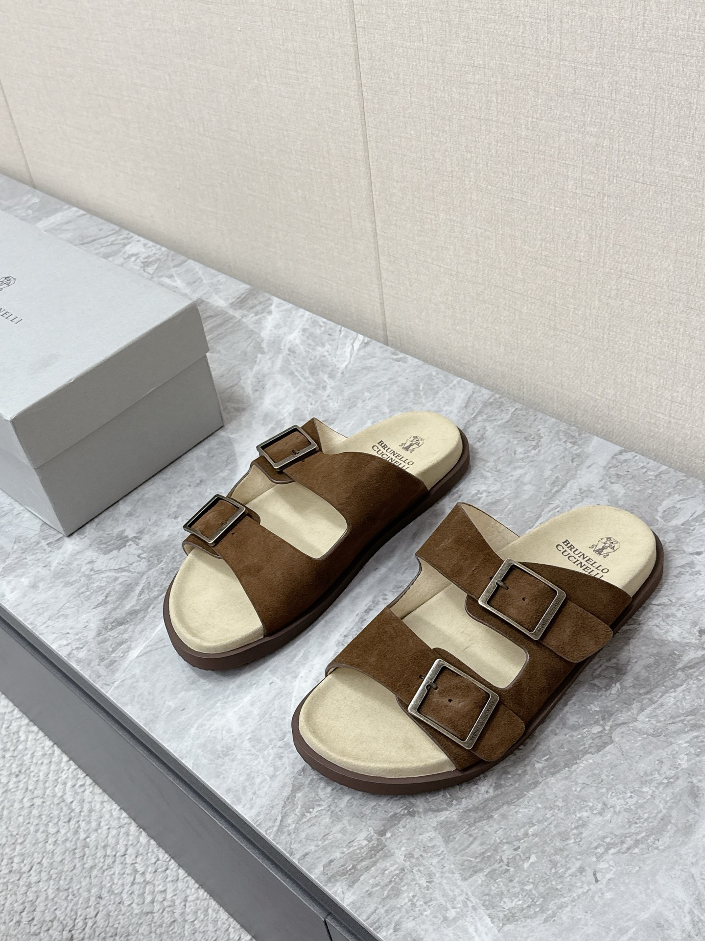 NO:889941,Brunello Cucinelli double-button suede old-money style slippers. There are many celebrity Internet celebrities. Simple and retro 'Birkenstock style' style. The color scheme is mainly earth tones (dark brown, dark coffee, etc.). It is versatile and can be worn with casual shorts or linen shirts to create a resort style. It can also be worn with a relaxed feel for daily commuting. The upper is made of the brand's iconic washed suede material, which is soft and delicate to the touch.  It has a matte texture after special treatment. The footbed is soft leather of the same color and is printed with the brand logo. The two adjustable metal buckles are the iconic design of this slipper. The brand logo is engraved on the metal buckle. The tightness can be adjusted freely according to the shape of the foot. It takes into account the fit and the convenience of putting on and taking off. Original open mold non-slip outsole size 39-45, slippers, brunello cucinelli, slippers, shorts, shirts, chamois leather19860909Brunello Cucinelli布鲁奈罗·库奇内利 双扣麂皮老钱风拖鞋 超多明星网红种草 简约复古的“勃肯风”造型 配色以大地色系为主（深棕、深咖等） 百搭不挑穿搭 既可以搭配休闲短裤 亚麻衬衫打造度假风造型 也能适配日常通勤的松弛感穿搭鞋面采用品牌标志性的水洗麂皮材质 触感柔软细腻 经过特殊处理后自带哑光质感 鞋床为同色系的软质皮革 印有品牌标识 两条可调节的金属扣带是这款拖鞋的标志性设计 金属扣上刻有品牌logo 可根据脚型自由调节松紧 兼顾贴合度与穿脱的便捷性原版开模防滑大底码数39-45,拖鞋,brunello cucinelli,slippers,shorts,shirts,chamois leather,Women's Shoes