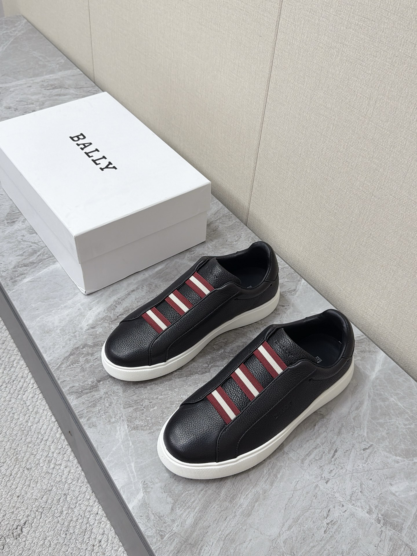 NO:931103,BALLY's latest red and white webbing slip-on casual sneakers. There are many celebrity Internet celebrities. The three-section red and white elastic webbing on the front of the shoe is BALLY's century-old iconic stripe symbol. Minimalist and low-recognition logo design. Low-key and light luxury. Integrated elastic webbing design without laces. No need to tie laces. Easy to put on and take off. Soft edging at the shoe. The upper is made of imported pebbled first-layer cowhide. The texture is fine and flexible, breathable and not stuffy to the feet.  Rounded low-cut toe to accommodate all types of feet without squeezing toes. Pure white thickened rubber flat bottom, non-slip and wear-resistant. Size 39-45, bally, cowhide19860909BALLY巴利最新款红白织带一脚蹬休闲板鞋 超多明星网红种草 鞋身正面三段式红白相间弹力织带 是BALLY百年标志性条纹符号 极简低辨识度logo设计 低调轻奢 无鞋带一体式弹力织带设计 无需系鞋带 穿脱便捷 鞋口柔软包边 鞋面采用进口荔枝纹头层牛皮 纹理细腻柔韧 透气不闷脚 圆润低帮鞋头 包容各类脚型 不挤压脚趾 纯白色加厚橡胶平底,防滑耐磨Size39-45,,bally,cowhide,Men's shoes