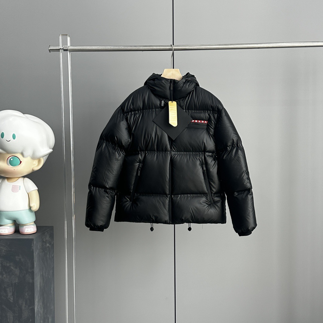NO:625232,The high version of the PRADA red label series men's hooded down jacket is definitely one of the best among this year's down jackets!  Filled with 90% white goose down, it has both resilience and warmth!  This product is made of top-quality nylon fabrics supplied by domestic customers. The surface of the fabric has a strong luster and a shiny color. The nylon fabric is soft and feels great. The whole body is waterproof and glued!  All splicing uses lamination technology and is fully waterproof!  The body is light and functional, and the heavy workmanship of this style can be seen through the taped strips of the lining details. Many details such as the placket zipper, lining pockets, side strips, and lower pockets all require heavy technical processing. The red taped strip letter logo on the left side of the chest brightens the overall style of the body, creating this season's P unique color matching aesthetics, a low-key and unobtrusive wearing style. Color Black Sizes s-m-l-xl-xxl,, prada, down  jacket,hats,alexander wang19860909高版本 PRADA红标系列男款连帽羽绒服 这款绝对是今年羽绒服中的翘楚数一数二！ 内填充90白鹅绒 ,回弹性与保暖性兼圣品！ 这款采用国内客供顶级的尼龙织物面料 面料表面的光泽感极强色泽油亮,尼龙织物的材质柔软手感巨好.全身防水压胶工艺！所有拼接全部采用压胶工艺,全方位防水！衣身质地轻盈兼具功能性,透过内衬细节的压胶条能看出此款的重工所在. 门襟拉链位置内衬口袋侧边条下侧口袋等多处细节,都需要重工进行的技术处理 胸前左侧红色压胶条字母标识点缀,提亮衣身整体格调,打造出本季P独特色彩搭配美学,低调而不张扬的穿着风格 颜色黑色 尺码s-m-l-xl-xxl,,prada,down jacket,hats,alexander wang,Men's clothing