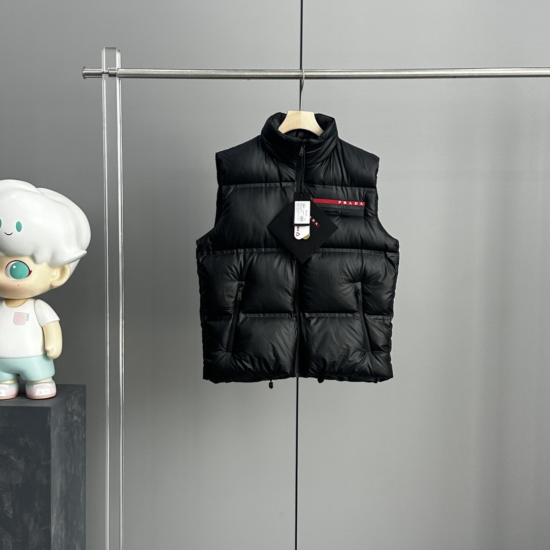 NO:625227,High version PRADA, new leather-labeled down vest for autumn and winter!  A super cost-effective casual down vest!  This down jacket is made of recycled polyester fiber materials supplied by customers. The fabric has extremely excellent waterproof and breathable properties. It can withstand the erosion of outdoor cold wind and rain. The touch of the fabric is unmatched and very soft!  Can bring you a comfortable wearing experience!  They have gone through a strict selection process and their fluffiness and resilience are extremely superior, and their cold-proof performance is beyond doubt!  Customized metal zippers and accessories are provided by customers. The classic leather label with customized brand logo on the chest is paired with a horizontal zipper design and diagonal pockets on both sides!  It shows off the aura of a big-name brand everywhere. The hooded design is simple and elegant. It looks good no matter how you wear it!  Double-layer lining with velvet-free high-density waterproof fabric, super windproof coefficient, excellent fluffiness and warmth!  Real stuff!  Color black, prada, prada, down jacket, hats, alexander wang19860909高版本 PRADA 普拉达,秋冬季皮标新款羽绒马甲！ 性价比超级高的休闲羽绒马甲！ 此款羽绒服甄选客供再生聚酯纤维材质制作而成 面料拥有极为优越的防水透气性 能抵挡户外寒风雨水的侵蚀,面料触感更是无人能敌 非常的柔软！能给你带来舒适的穿着体验！ 均经过严格的挑选工序 其蓬松感与与回弹性都极为优越,御寒性能更是毋庸置疑！ 客供定制金属拉链与辅料 胸前经典的定制品牌logo皮标,搭配横拉链设计,双侧斜插口袋！ 无处不在彰显大牌气场,连帽设计、简约大气 怎么穿怎么好看 ！双层内衬不出绒高密度防水布料 防风系数超强,蓬松度和保暖性极佳！真正的牛货！ 颜色黑色,,prada,prada,down jacket,hats,alexander wang,Men's clothing