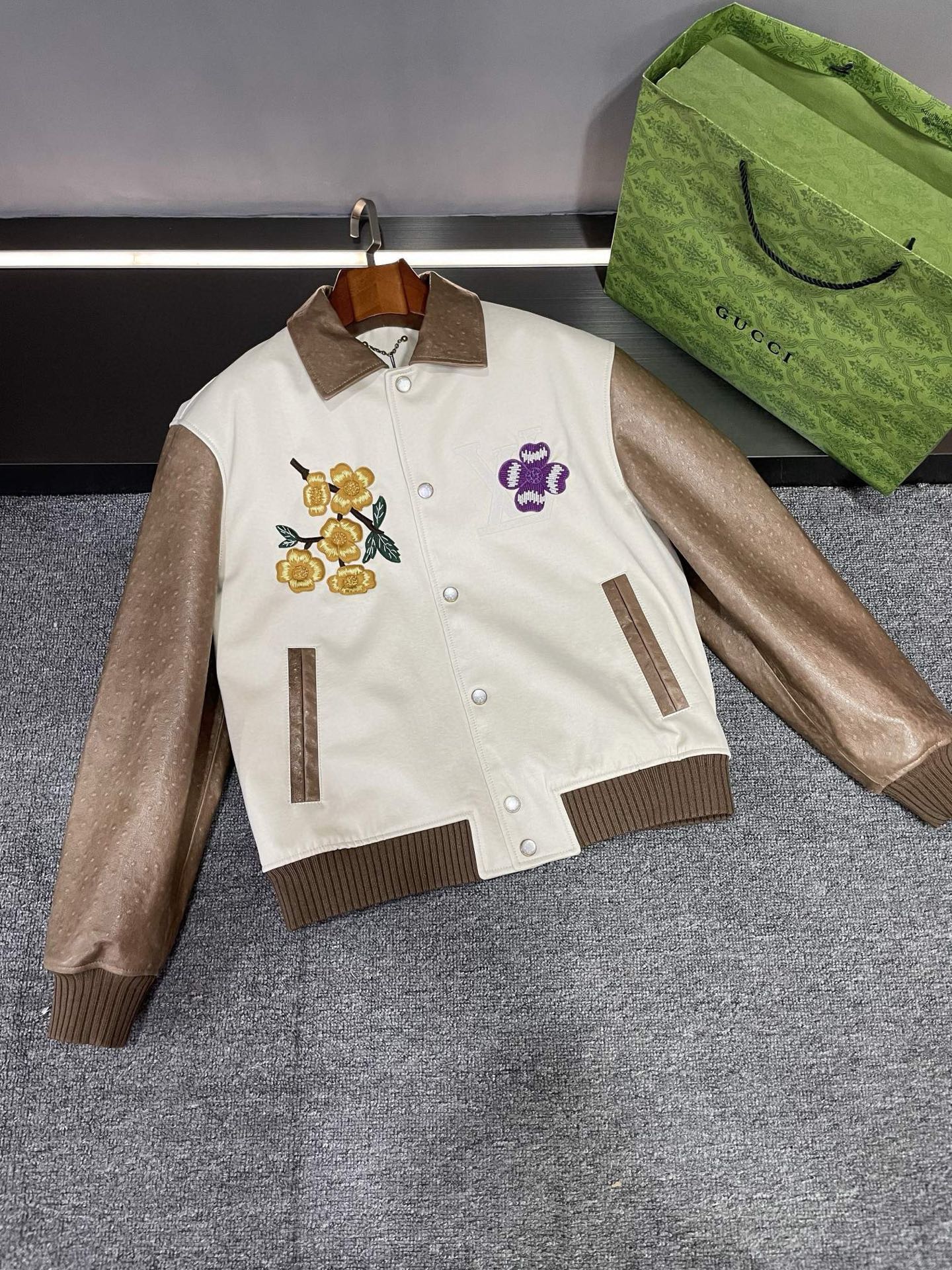 NO:855004,[Louis Vuitton LV 25 new autumn and winter men's ostrich leather leather jacket, the perfect fusion of luxury and fashion] Tiled details - Louis Vuitton 25 new autumn and winter men's ostrich leather leather jacket. The design of Louis Vuitton's leather jacket is unique, the sleeves and collar are made of brown ostrich leather, and the natural grain texture exudes an unparalleled luxurious texture. Each texture is a masterpiece of nature, as if telling a unique story.  The body part is made of pure cotton off-white denim, which not only adds a casual feel, but also complements the nobility of ostrich leather. This unique combination of materials allows you to feel comfortable and at ease while showing your fashion taste. The heavy three-dimensional embroidery on the chest and back is a highlight. LV brand LOGO  The flowers and brand elements are lifelike, as if they are works of art carefully carved by the artist. Every stitch and every thread embodies exquisite craftsmanship and the ultimate pursuit of details. The pearl-engraved buttons with the latest design language of Lujia add a sense of sophistication and elegance to this leather jacket. These small buttons are like bright pearls, exuding a charming light, making you the center of attention inadvertently. Lv  The new autumn and winter men's ostrich leather leather jacket is not only a piece of clothing, but also a symbol of lifestyle. It perfectly integrates luxury and fashion, allowing you to exude confidence and charm in any occasion. If you are eager to own a unique fashion item, then this leather jacket is definitely your best choice. Come and feel its charm!   Size M-3XL,,louis vuitton,louis vuitton,louis vuitton,louis vuitton,leather jacket,ostrich skin,Top Customize119860909【路易威登 LV 25 秋冬新款男士鸵鸟皮皮衣,奢华与时尚的完美融合】  平铺细节图——路易威登 25秋冬新款男士鸵鸟皮皮衣.  路易威登 这款皮衣的设计独具匠心,袖子和领子采用棕色鸵鸟皮,天然的颗粒纹路散发着无与伦比的奢华质感.每一道纹路都是大自然的杰作,仿佛在诉说着一段独特的故事.  身子部分则选用纯棉米白色牛仔布,既增添了休闲感,又与鸵鸟皮的高贵相得益彰.这种独特的材质组合,让你在展现时尚品味的同时,也能感受到舒适与自在.  胸前和后背的重工立体刺绣更是一大亮点.LV 品牌 LOGO 和品牌元素花卉栩栩如生,仿佛是艺术家精心雕琢的艺术品.每一针每一线都凝聚着精湛的工艺和对细节的极致追求.  而驴家最新设计语言的珍珠刻字纽扣,则为这款皮衣增添了一份精致与优雅.这些小小的纽扣如同璀璨的明珠,散发着迷人的光芒,让你在不经意间成为众人瞩目的焦点.  Lv 秋冬新款男士鸵鸟皮皮衣,不仅仅是一件衣服,更是一种生活方式的象征.它将奢华与时尚完美融合,让你在任何场合都能散发出自信与魅力.如果你渴望拥有一件与众不同的时尚单品,那么这款皮衣绝对是你的不二之选.快来感受它的魅力吧！  码数M-3XL,,louis vuitton,louis vuitton,louis vuitton,louis vuitton,leather jacket,ostrich skin,Top Customize1,Men's clothing