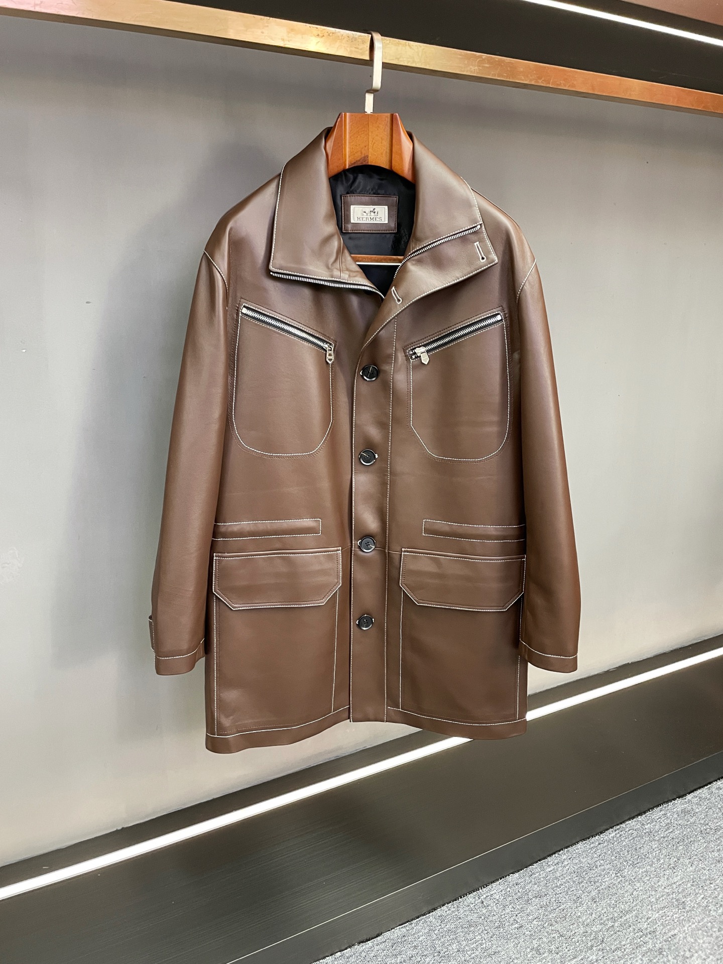 NO:814450,Hermes 2025 Autumn and Winter Men's Long Sheepskin Trench Coat Hunting Style and Craftsmanship Symbiosis In the change of time in the 2025 Autumn and Winter, Hermès takes equestrian heritage as its bones and exquisite craftsmanship as its soul, and presents new men's long sheepskin trench coats, building a clothing refuge with both warmth and style for urban gentlemen.  Crafted from brown sheepskin imported from New Zealand, this material originates from the 'nobles of leather' and has outstanding texture due to the local pleasant climate and strict animal husbandry regulations - the leather is as fine and soft as velvet, warm to the touch and elastic. After being treated with advanced tanning processes,  The color is uniform and mellow, retaining the rustic charm of the natural texture while also being durable against wear. The tight fiber structure gives it excellent thermal insulation properties, injecting continuous warmth into the cold autumn and winter, and the environmentally friendly processing concept echoes the brand's insistence on sustainability.  The mid-length version cleverly balances the proportions of the body shape, which not only ensures the protection area in winter, but also does not appear cumbersome, and is suitable for various scenes. The classic hunting suit style runs through the design, continuing Hermès’ profound equestrian inspiration genes, with a neat silhouette that hides an adventurous spirit and a soft shoulder line.  But without losing the sense of strength, it outlines a calm and upright gentleman's silhouette. The white stitching all over the body is like precise brushstrokes, which outlines the body lines with sharp visual contrast. The fine stitching from the hem to the sleeve edges is not only a precise interpretation of the structural beauty, but also demonstrates the exquisite craftsmanship of a saddle maker.  From urban commuting to outdoor travel, this Hermes windbreaker has become a timeless item that spans occasions with its luxurious material, practical shape and exquisite details, witnessing Hermès' unremitting pursuit of 'practical aesthetics'. Size 48-56,,hermes,hermes,sheepskin,Top Customize119860909Hermes 爱马仕 2025秋冬男士长款羊皮风衣猎装格调与匠艺共生 在2025秋冬的时序更迭中,爱马仕以马术传承为骨、精湛工艺为魂,呈现男士长款羊皮风衣新作,为都市绅士构筑兼具温度与格调的穿着庇护所. 甄选新西兰进口棕色羊皮匠心打造,这份源自“皮中贵族”的材质,因当地宜人气候与严格畜牧规范而质地出众——皮质细腻柔软如绒,触感温润且富有弹性,经先进鞣制工艺处理后,色泽均匀醇厚,既保留天然纹理的质朴韵味,又兼具抗磨损的耐用特性.紧密的纤维结构赋予其优异保暖性能,为凛冽秋冬注入持续暖意,而环保加工理念更呼应品牌对可持续性的坚守. 中长版型巧妙平衡身形比例,既保障冬日防护面积,又不显拖沓累赘,适配多元场景穿搭.经典猎装风格贯穿设计,延续爱马仕深厚的马术灵感基因,于利落轮廓中暗藏冒险精神,肩线柔和却不失力量感,勾勒出从容挺拔的绅士剪影.全身白色车线如精准笔触,以鲜明视觉对比勾勒衣身线条,从衣摆至袖缘的细密针脚,既是对结构美的精准诠释,更彰显马鞍匠般的精湛工艺. 从都市通勤到户外出行,Hermes 这件风衣以材质的奢适、版型的实用与细节的精致,成为跨越场合的永恒单品,见证爱马仕对“实用美学”的不懈追求. 码数48-56,,hermes,hermes,sheepskin,Top Customize1,Men's clothing