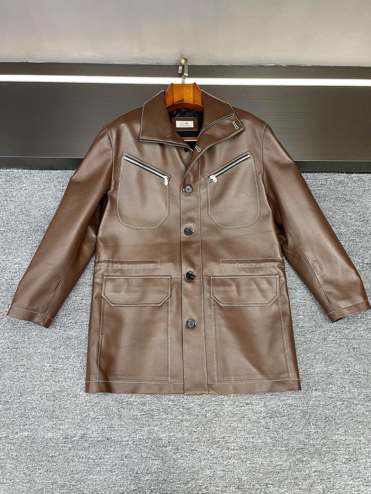 NO:855073,Hermes Autumn and Winter Goddess Style｜Safari-style sheepskin windbreaker knows the aesthetics of men so well that Hermes Autumn and Winter Men's Windbreaker has been mastered!  This is the perfect balance between high-end texture and practical aesthetics. The brown sheepskin imported from New Zealand has a delicate and warm luster. It feels soft and waxy yet firm to the touch. It is warm when worn in autumn and winter without looking bulky. The mid-length version is friendly to all body shapes. The length that just covers the buttocks is neat and tall, giving you a calm aura when walking.  The most striking thing is the classic safari style design, which has a retro and uninhibited style. It abandons superfluous decoration but hides ingenuity in the details - the whole body top stitching uses contrasting white stitching to accurately outline the outline of the body, and the lines on the shoulder line and pocket edges are instantly full. The low-key hides the delicacy visible to the naked eye.  When commuting, wear a high-neck knitted jacket and trousers, making you a relaxed urban elite; wear leather boots with jeans on the weekend, and you can switch into a retro man with a sense of story. One piece can be worn in many scenes, this is a classic investment model that can be worn for many years. Size 48-56,,hermes,hermes,boots,jeans,sheepskin,Top Customize119860909Hermes 爱马仕秋冬封神款｜猎装风羊皮风衣太懂型男审美 被 Hermes 爱马仕 秋冬男士风衣狠狠拿捏了！这才是高阶质感与实用美学的完美平衡 一眼沦陷的新西兰进口棕色羊皮,自带细腻温润的光泽感,上手触感软糯却不失挺括筋骨,秋冬穿既保暖又不会显得臃肿.中长版型对各种身形都很友好,恰好盖过臀部的长度利落显高,行走间全是从容气场. 最戳人的是经典猎装风设计,自带复古又不羁的格调,摒弃了多余装饰却在细节处藏满巧思——全身明线采用对比强烈的白色车线,将衣身轮廓精准勾勒,肩线、口袋边缘的线条感瞬间拉满,低调中藏着肉眼可见的精致. 通勤时内搭高领针织与西裤,是松弛有度的都市精英；周末换上皮靴配牛仔裤,又能切换成自带故事感的复古型男.一件穿越多种场景,这才是能穿多年的经典投资款. 码数 48-56,,hermes,hermes,boots,jeans,sheepskin,Top Customize1,Men's clothing