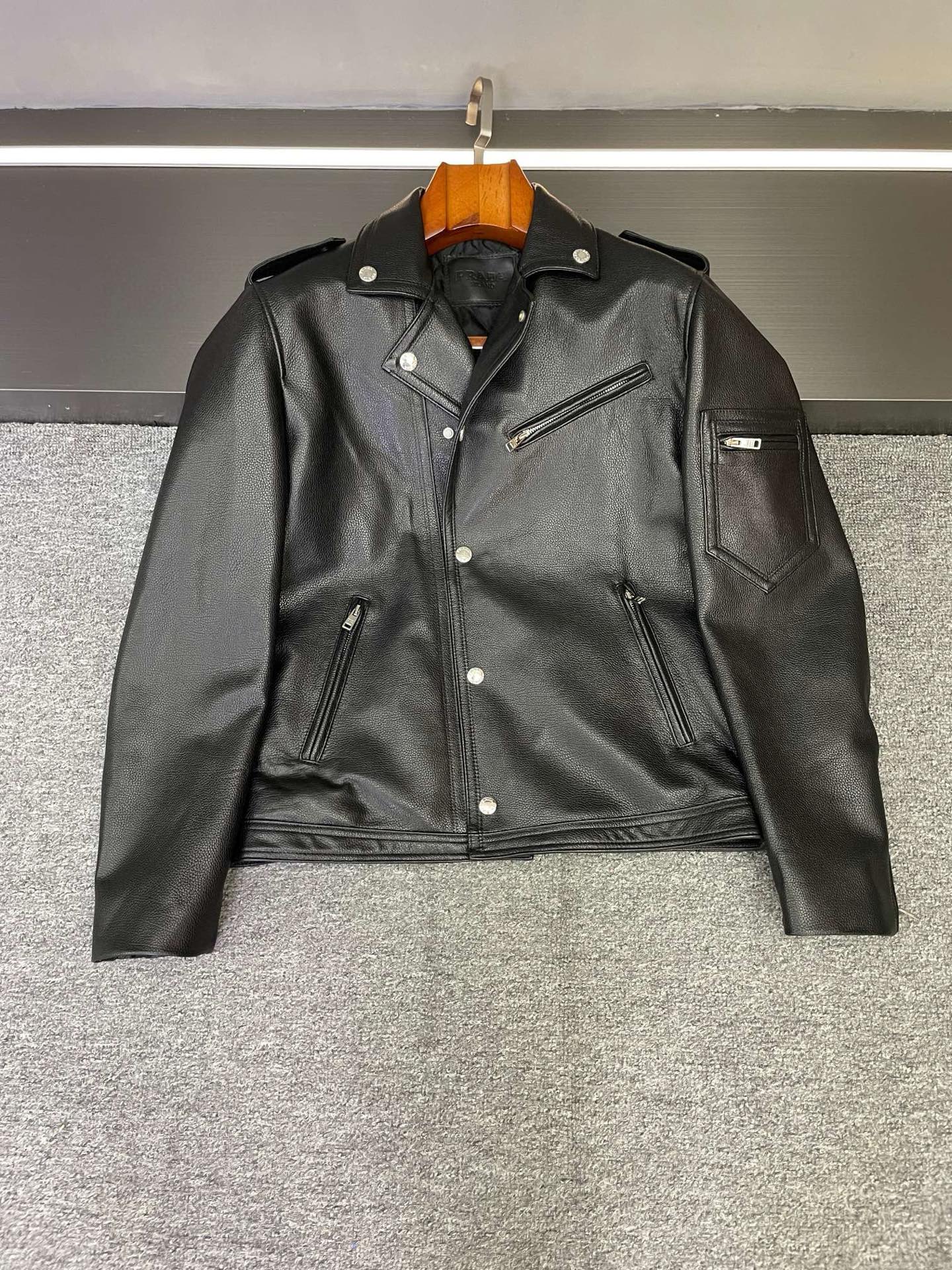 NO:772354,Who knows?  Wear Prada's new motorcycle suit and become cool in seconds. Cool guys gather!  Prada's new 2026 spring and summer men's leather motorcycle suits make a grand debut, and it's finally our turn to be so handsome!   Selected Spanish black first-layer calfskin is warm to the touch, delicate and firm, and every inch tells the story of craftsmanship and texture. The pebbled pattern design, with regular and three-dimensional texture, is like putting a layer of natural armor on the leather jacket, giving it a full sense of high-end, and it is also super wear-resistant, making it taste more timeless.  Prada's classic motorcycle suit upper body instantly changes into right-angled shoulders, with neat and smooth lines, interpreting effortless fashion. Thin cotton is added to the lining, which is warm and not bulky. You will no longer be afraid of the cold when going out in autumn and winter, and you can control your style and temperature. The low-key triangle logo on the chest is revealed inadvertently, and knowledgeable people can get your fashion taste at a glance.  Whether paired with overalls or jeans, you can easily create a street trend. This autumn and winter, wear it when you go out, and you will be the most handsome boy on the street!   Size M-3XL,,prada,prada,jeans,leather jacket,cowhide,Top Customize119860909谁懂啊！穿上Prada新款机车服秒变酷盖  酷盖们集合！Prada 2026春夏新款男士牛皮机车服重磅登场,这泼天的帅气终于轮到咱们了！  精选西班牙黑色头层小牛皮,触手温热,细腻紧实,每一寸都诉说着匠心与质感.荔枝纹设计,纹理规则又立体,就像给皮衣披上了一层天然铠甲,高级感拉满,还超抗造耐磨,越穿越有味道.  普拉达机车服经典版型上身秒变直角肩,线条利落流畅,诠释着毫不费力的时髦.内里加薄棉,温暖又不臃肿,秋冬出街再也不怕冷,风度温度统统拿捏.胸前低调的三角标,不经意间露出,懂行的人一眼就能get到你的时尚品味.  无论是搭配工装裤还是牛仔裤,都能轻松打造街头潮流感.这个秋冬,穿上它出门,你就是街头最靓的仔！  码数M-3XL,,prada,prada,jeans,leather jacket,cowhide,Top Customize1,Men's clothing