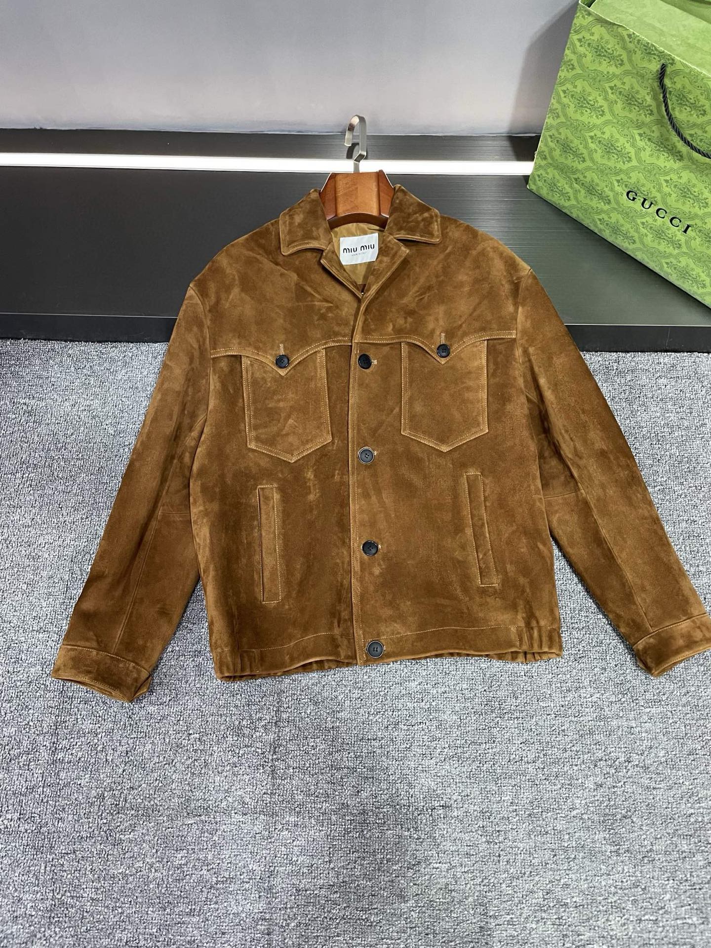 NO:772046,MIU MIU 2026 Spring and Summer New Men's Sheepskin Leather Jacket, Detailed Layout. The brown suede sheepskin imported from Australia has extraordinary texture. You can feel the gift of nature when you touch it. The design of the small suit collar is elegant and capable, and fully demonstrates the maturity and stability of men. The flap pocket on the chest is designed in a lotus leaf shape, which is unique and adds a sense of agility and playfulness to the overall look. Then the MIU MIU brand below the collar  The leather embroidery of the LOGO is a low-key demonstration of the brand's luxury and quality. This MIU MIU leather jacket is not only a piece of clothing, but also an attitude towards life. Wear it and you will be the gentleman who stands out from the crowd, exuding confidence and charm. Whether it is business occasions or leisure time, MIU MIU's men's sheepskin leather jacket can be your best partner. The best choice. Size M-3XL,,miumiu,leather jacket,business suit,sheepskin,Top Customize119860909缪缪 MIU MIU 2026春夏新款男士羊皮皮衣,平铺细节图  精选澳洲进口棕色反绒羊皮,质感非凡,触摸之间仿佛能感受到大自然的馈赠.小西装领的设计,优雅中透露着干练,将男性的成熟稳重展现得淋漓尽致.  胸前的揭盖口袋设计成荷叶状,别出心裁,为整体造型增添了一份灵动与俏皮.而后衣领下方的 MIU MIU 品牌 LOGO 贴皮绣,更是低调地彰显着品牌的奢华与品质.  MIU MIU这款皮衣不仅是一件衣服,更是一种生活态度.穿上它,你就是那个在人群中脱颖而出的绅士,散发着自信与魅力.  无论是商务场合还是休闲时光,MIU MIU 这款男士羊皮皮衣都能成为你的最佳搭档.不二之选.  码数M-3XL,,miumiu,leather jacket,business suit,sheepskin,Top Customize1,Men's clothing