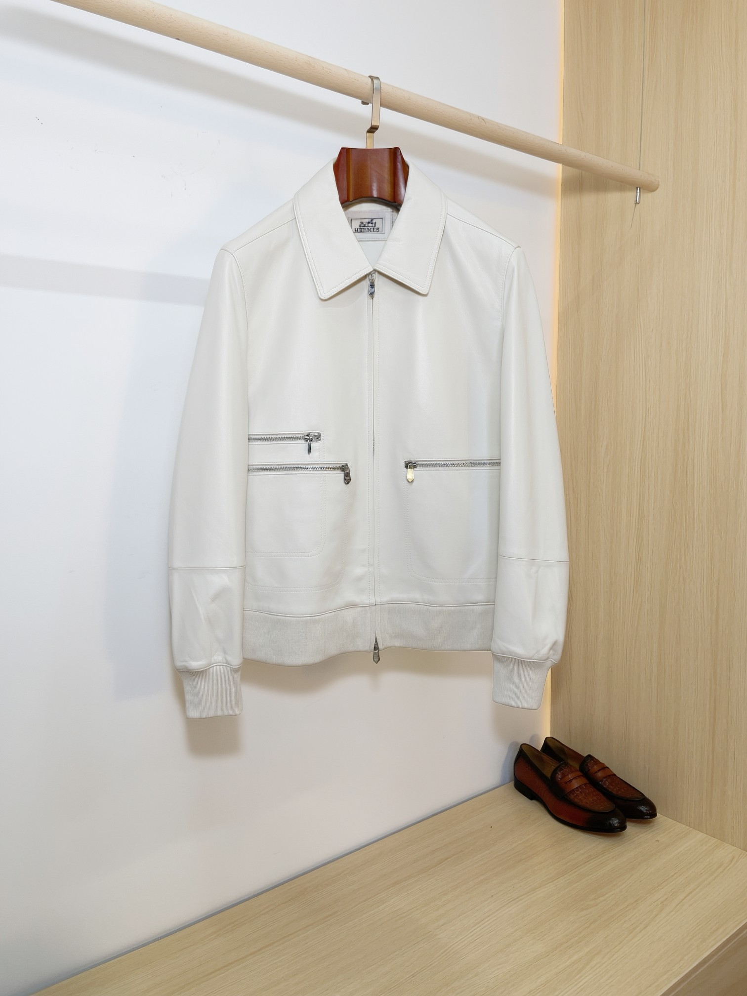 NO:940553,Hermès minimalist lapel sheepskin bomber jacket Hermès classic casual leather jacket, minimalist and neat lapel baseball jacket style, regardless of body shape or outfit, can be used for business commuting, daily leisure, and motorcycle style. Imported first-layer sheepskin is selected, the leather surface is delicate, soft and has a soft light texture. It is soft and skin-friendly and has high toughness. It is not easy to get hard and wrinkle after long-term wear.  The neat full-zipper placket and multiple zipper cargo pockets on the front are both decorative and practical. The hardware details are matte and high-end, low-key and not exaggerated; the hem + ribbed cuffs, the classic baseball uniform structure, firmly locks the shape, and the upper body looks slim and neat, without being bulky and dragging.  The lining is custom-made with a smooth and skin-friendly lining, and the stitching is neat and precise. The entire garment is clean and smooth with no redundant design, which perfectly interprets Hermès' 'less is more' top-notch luxury aesthetics. Available in black and white, black is calm and elegant, and off-white is clean and elegant. A men's wardrobe that has been worn for many years and will never go out of style just needs hard goods, and the light luxury texture can be filled directly. Size M-3XL,,hermes,hermes,jackets & coats,leather jacket,sheepskin,Top  Customize119860909爱马仕 Hermès极简翻领羊皮飞行员夹克  爱马仕经典休闲皮衣天花板,极简利落的翻领棒球夹克版型,不挑身材不挑穿搭,商务通勤、日常休闲、轻机车风全能驾驭.  甄选进口头层绵羊皮,皮面细腻柔润自带柔光质感,软糯亲肤同时韧性十足,久穿不易发硬起皱. 利落全开拉链门襟,前身多拉链工装口袋,兼具装饰性与实用性,五金细节哑光高级,低调不浮夸；下摆+罗纹收口袖口,经典棒球服结构,牢牢锁住版型,上身显瘦利落,不臃肿拖沓.  内里定制顺滑亲肤里布,走线工整精密,整件衣服剪裁干净流畅,没有多余冗余设计,完美诠释爱马仕「少即是多」的顶级轻奢美学. 黑白双色可选沉稳黑低调显贵,米白干净儒雅,一件穿多年,永不过时的男士衣橱刚需硬货,轻奢质感直接拉满. 码数M-3XL,,hermes,hermes,jackets & coats,leather jacket,sheepskin,Top Customize1,Men's clothing