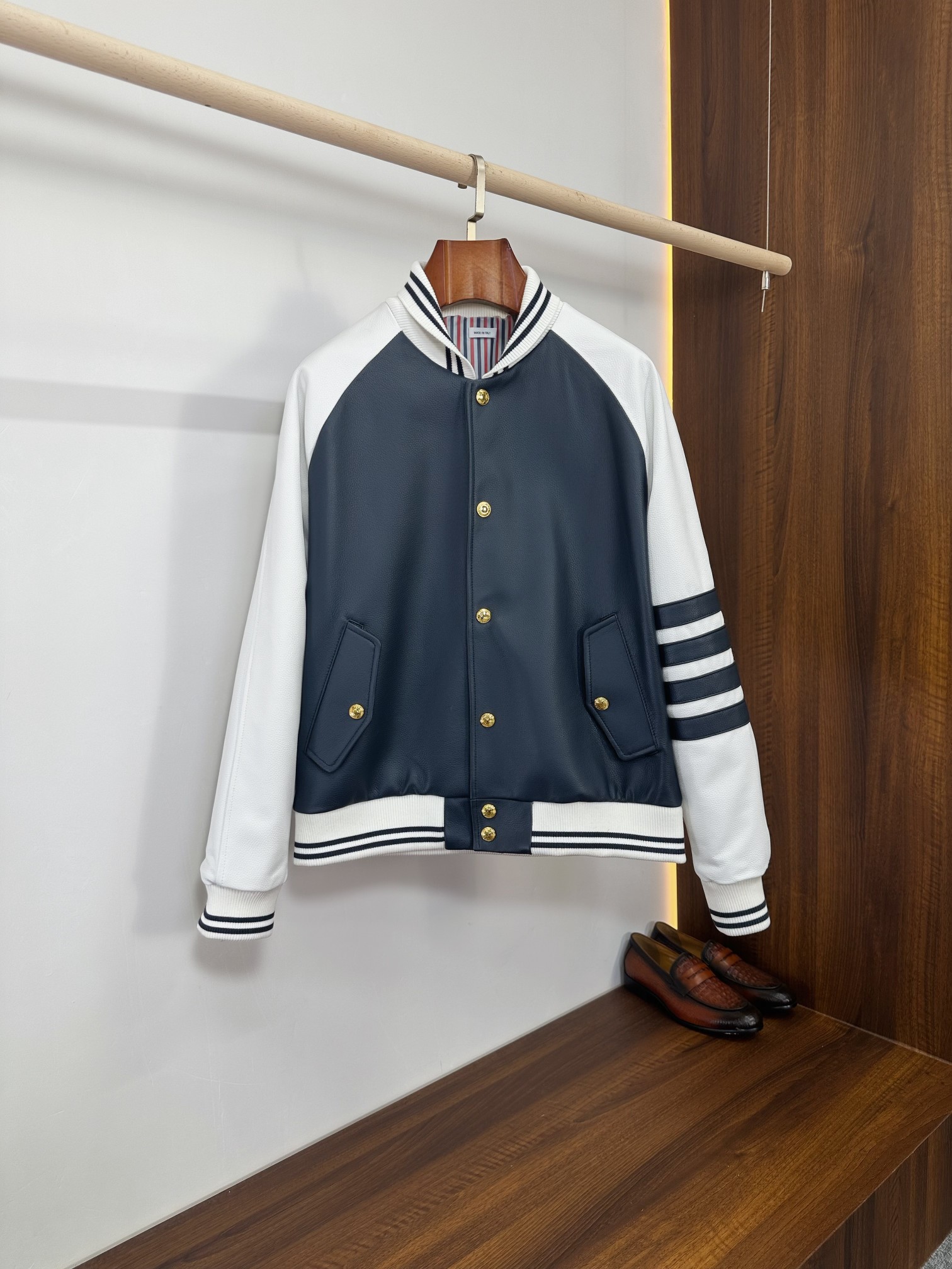 NO:940598,Thom Browne's classic four-stripes color-blocked sheepskin baseball jacket | Light luxury casual evergreen model Thom Browne's iconic baseball uniform version, navy blue + white contrast stitching, the body is made of imported pebbled sheepskin, the sleeves are spliced with soft waxy sheepskin, and the iconic four-stripes elements are added. The brand's classic red, white and blue striped lining is on the inside, with a light luxury college style. It is versatile for commuting, daily life, and leisure. It is a high-end genuine leather jacket that can be worn in all seasons. Fabric texture  The front and back of the body are made of high-definition pebbled first-layer sheepskin, with full and natural grain grains, flexible and anti-wrinkle, breathable and skin-friendly, with a delicate and soft touch, without any hard and bulky feel. The raglan sleeves are made of milky white softened sheepskin.  The dark and light contrasting colors are full of layering. The matte leather is low-key and high-end. It is durable and not easy to crack or fade. It is refreshing and neat to wear alone in spring and autumn. It is casual and stylish when layered with sweaters and shirts in early winter. The leather will become warmer and textured after long-term wear.  Core detail design: classic stand-up baseball collar, black and white striped rib cuffs, moderate elasticity, fit the neck, windproof and warm. The placket uses retro gold metal snaps, which are evenly arranged, open and close neatly, and the hardware gloss is delicate and thick, restoring the original texture of the brand.  The diagonal patch pockets on both sides are matched with metal buckles of the same color, taking into account both decoration and practicality, making it easy to store small items. The iconic navy four-stripe stripes on the sleeves are the soul logo of the TB brand, simple but highly recognizable. The back collar is embellished with a small red, white and blue webbing logo, which is a low-key finishing touch.  The interior is made of TB's exclusive red, white and blue vertical stripes custom-made lining, with neat and dense wiring, fine hemming and no excess threads. Open the inside to reveal the brand's exclusive details, and the materials and workmanship used inside and outside are both online. Fitted with a short baseball cut, raglan sleeves weaken the restriction of shoulder width, and both slim and slightly fat figures can look neat and youthful and have a light and luxurious gentleman's temperament. Suitable for wearing scenarios.  It can be perfectly worn for daily shopping, campus style, light business commuting, weekend parties, and short trips. Wear it with a solid-color round-neck T-shirt, knitted bottoms, and straight casual pants, jeans, khaki pants, white shoes, and loafers to easily create an American light luxury college style; you can also wear a turtleneck sweater to create a calm urban elite feel.  There is no overly exaggerated design, relying on the brand's classic four-stripes, contrasting leather and striped lining to highlight the style. It is low-key and elegant, and can be easily controlled by young and mature men. It is reserved for high-end and can be recognized and classed as a gift. Size M-3XL,,thom browne,loafers,jeans,jackets & coats,jackets & coats,sweaters,shirts,tees,t-shirt,sheepskin,Top Customize119860909Thom Browne经典四道杠拼色羊皮棒球夹克｜轻奢休闲常青款  汤姆布朗标志性棒球服版型,藏青+白色撞色拼接,衣身主体进口荔枝纹羊皮打造,袖子软糯羊皮拼接,标志性四道杠元素加持,内里品牌经典红白蓝条纹里布,轻奢学院风拉满,通勤、日常、休闲百搭不挑人,是四季实穿的高端真皮外套.  面料质感  衣身前片与后背采用高定荔枝纹头层羊皮,纹路颗粒饱满自然,柔韧抗皱、透气亲肤,触感细腻软糯,完全没有硬皮笨重感.插肩袖为奶白色柔化羊皮,深浅撞色层次感十足,哑光皮质低调高级,耐穿不易开裂掉色,春秋单穿清爽利落,初冬内搭毛衣、衬衫叠穿随性有型,长期穿着皮质愈发温润有质感.  核心细节设计  经典立领棒球领口,黑白条纹罗纹收口,弹性适中,贴合颈部且防风保暖.门襟采用复古金色金属按扣,均匀排布,开合利落,五金光泽细腻厚重,还原品牌原版质感. 两侧斜向贴袋搭配同色系金属扣,兼顾装饰性与实用性,随身小物件轻松收纳；袖子标志性藏青四道杠条纹,是TB品牌灵魂标识,简约却极具辨识度.后背领尾点缀红白蓝织带小标,低调点睛. 内里通体TB专属红白蓝竖条纹定制里布,走线工整密实,包边精细无多余线头,翻开内侧即是品牌专属细节,内外用料做工双在线.合身短款棒球剪裁,插肩袖弱化肩宽限制,瘦身材、微胖身形都能穿出利落少年感与轻奢绅士气质.  穿搭场景适配  日常逛街、校园风穿搭、轻商务通勤、周末聚会、短途出游都能完美驾驭.内搭纯色圆领T恤、针织打底,下装搭配直筒休闲裤、牛仔裤、卡其西裤,配小白鞋、乐福鞋,轻松打造美式轻奢学院风；也可内搭高领羊毛衫,打造沉稳都市精英感. 无过度浮夸设计,依靠品牌经典四道杠、撞色皮料与条纹内衬凸显格调,低调显贵不张扬,年轻人、轻熟男士都能轻松驾驭,自留高级,送礼辨识度与档次双在线. 码数M-3XL,,thom browne,loafers,jeans,jackets & coats,jackets & coats,sweaters,shirts,tees，t-shirt,sheepskin,Top Customize1,Men's clothing