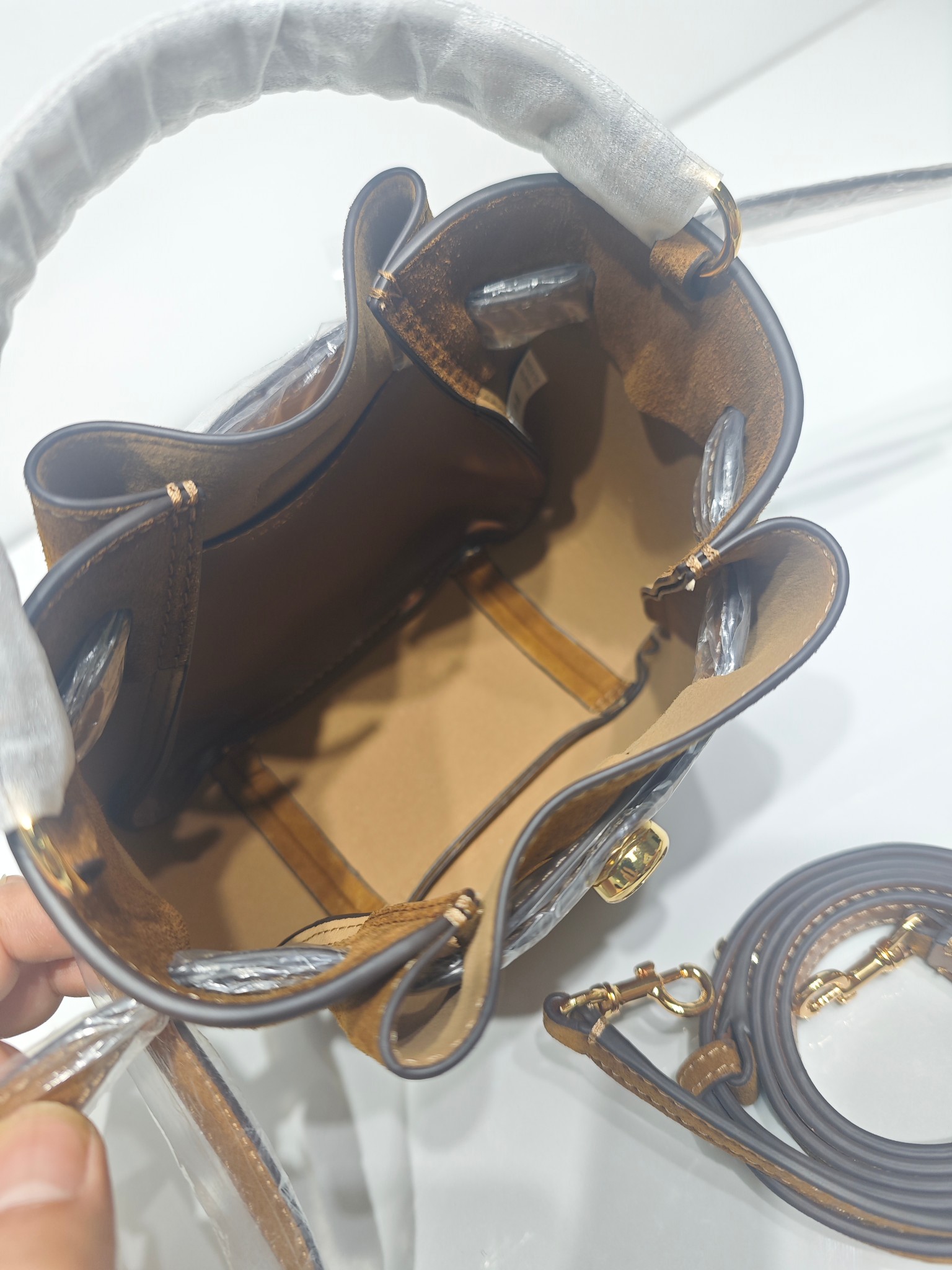 原单P380
❤️迷你miniTB新款 Romy 水桶包，精选柔软皮革，廓形灵巧，顶部巧妙收拢，富有质感。这款水桶包适合日常出行使用，轻盈灵活，包内空间宽敞，贴心配备一个口袋，方便有序收纳。配有纤细背带，并融入全新纽扣式 Logo，增添时尚亮点。可手提或斜挎，满足多样穿搭需求。磁力按扣；背带设有钉扣
尺寸18&times;8&times;15
编号179988