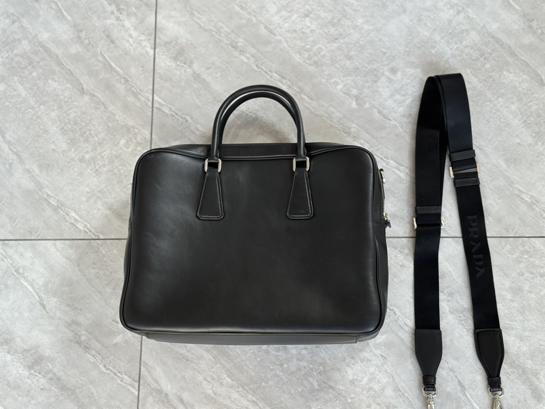 Real shots of Pradas 24 mens double zipper thick briefcases. This elegant, versatile leather satchel is designed with two compartments and featur