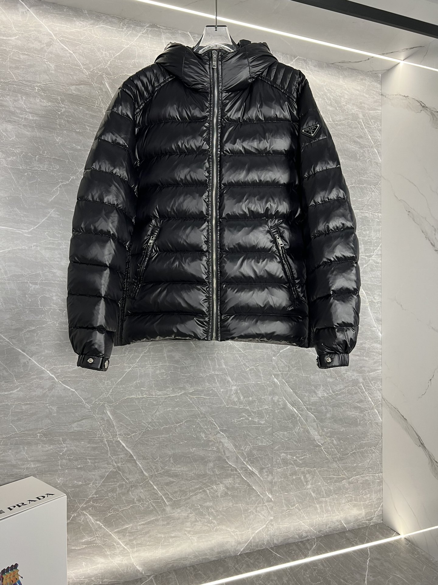 Prada hooded down jacket with oversized fit, quilted design, 90% down fill, enamel triangle logo. Sizes 48-56 in black/blue.-Big cat