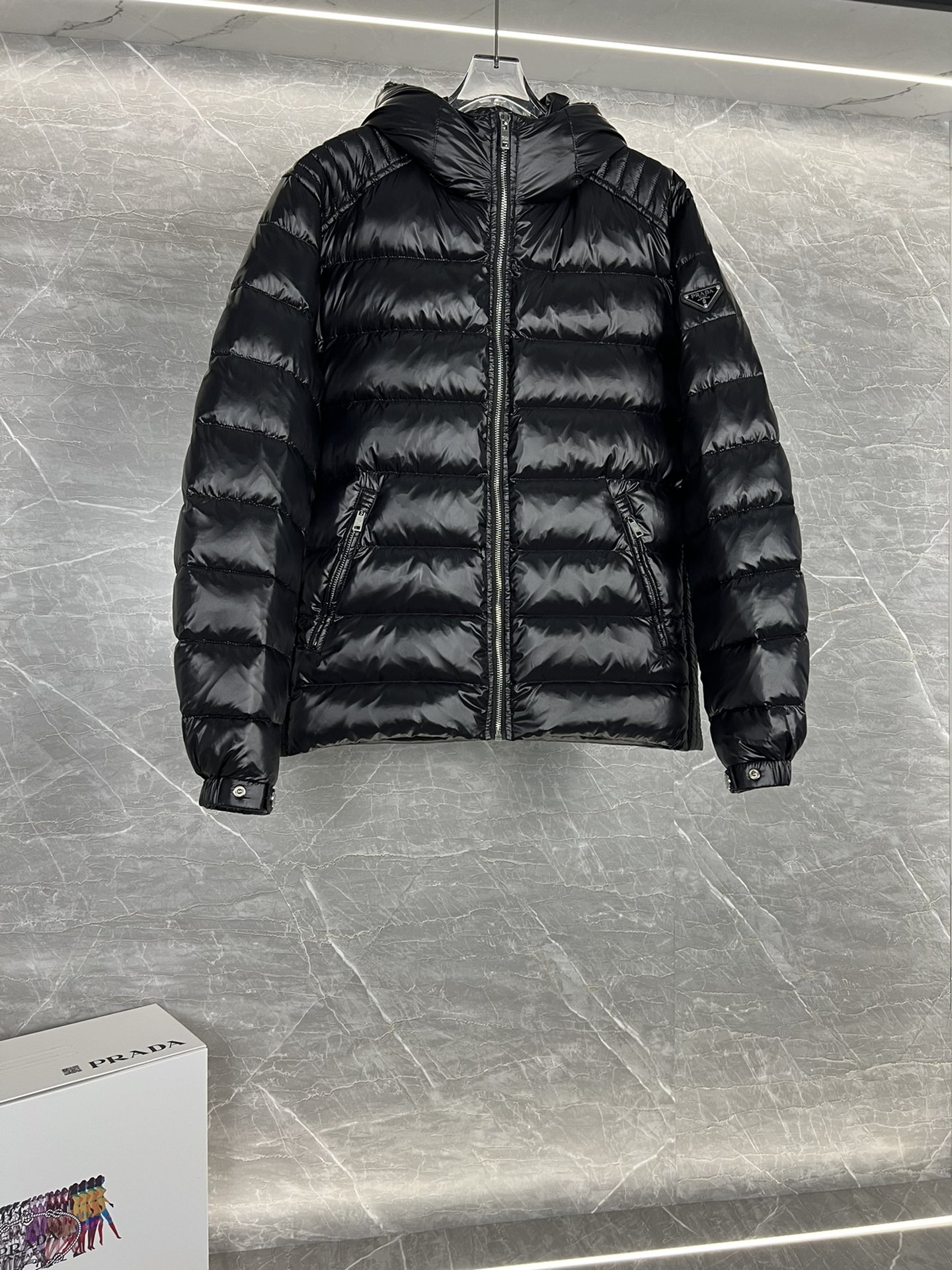 Prada hooded down jacket with oversized fit, quilted design, 90% down fill, enamel triangle logo. Sizes 48-56 in black/blue.-Big cat