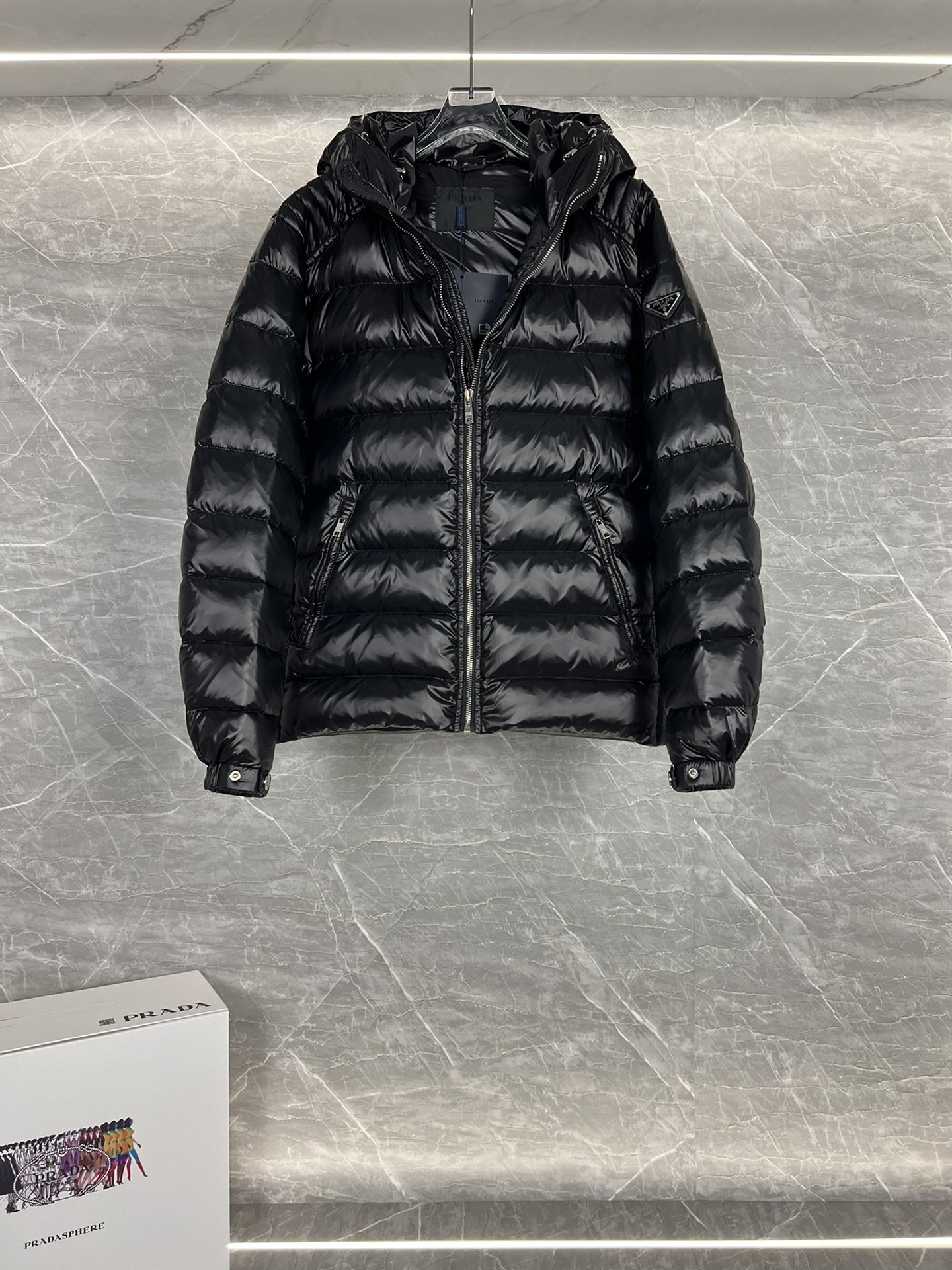 Prada hooded down jacket with oversized fit, quilted design, 90% down fill, enamel triangle logo. Sizes 48-56 in black/blue.-Big cat