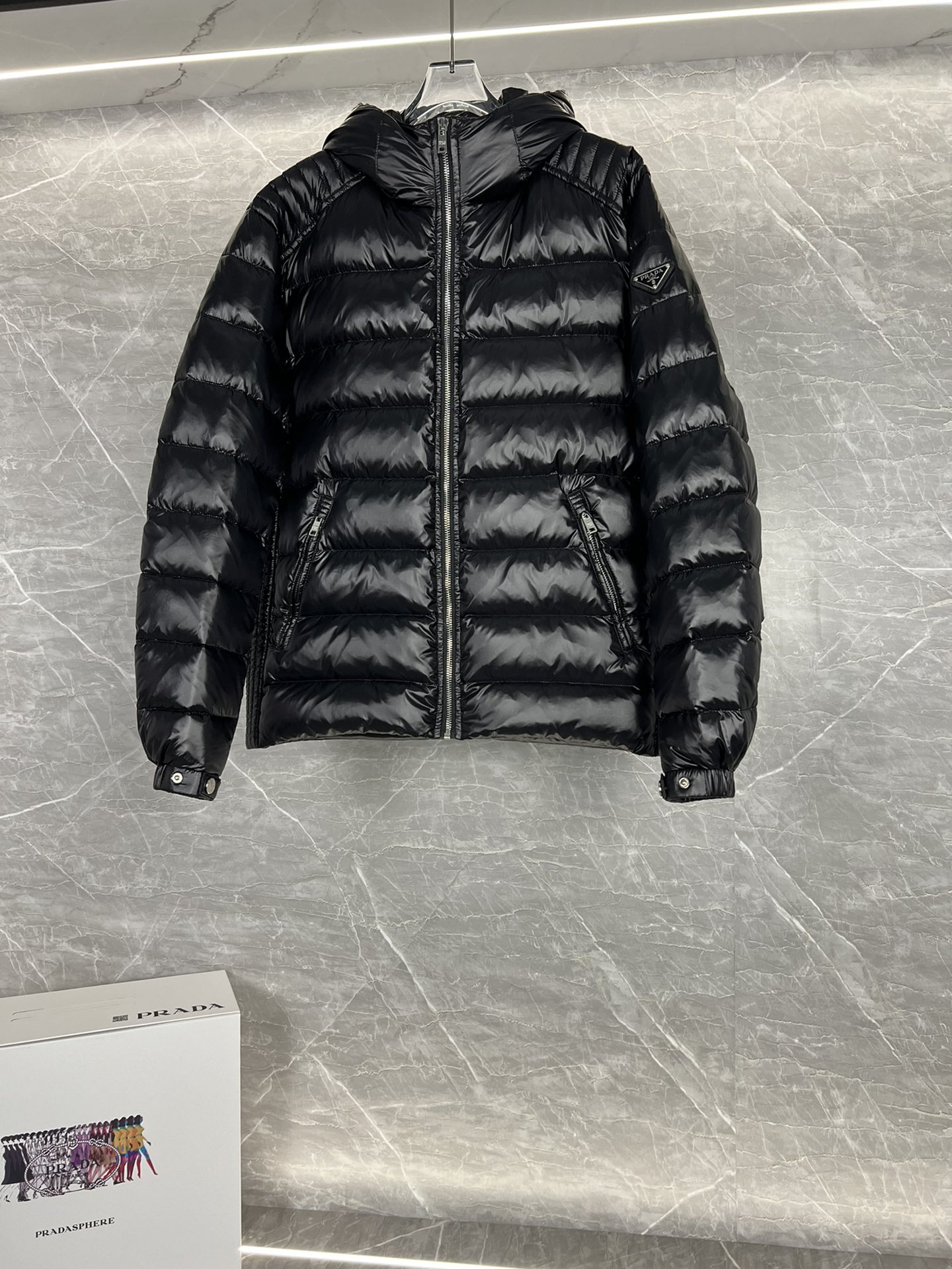 Prada hooded down jacket with oversized fit, quilted design, 90% down fill, enamel triangle logo. Sizes 48-56 in black/blue.-Big cat