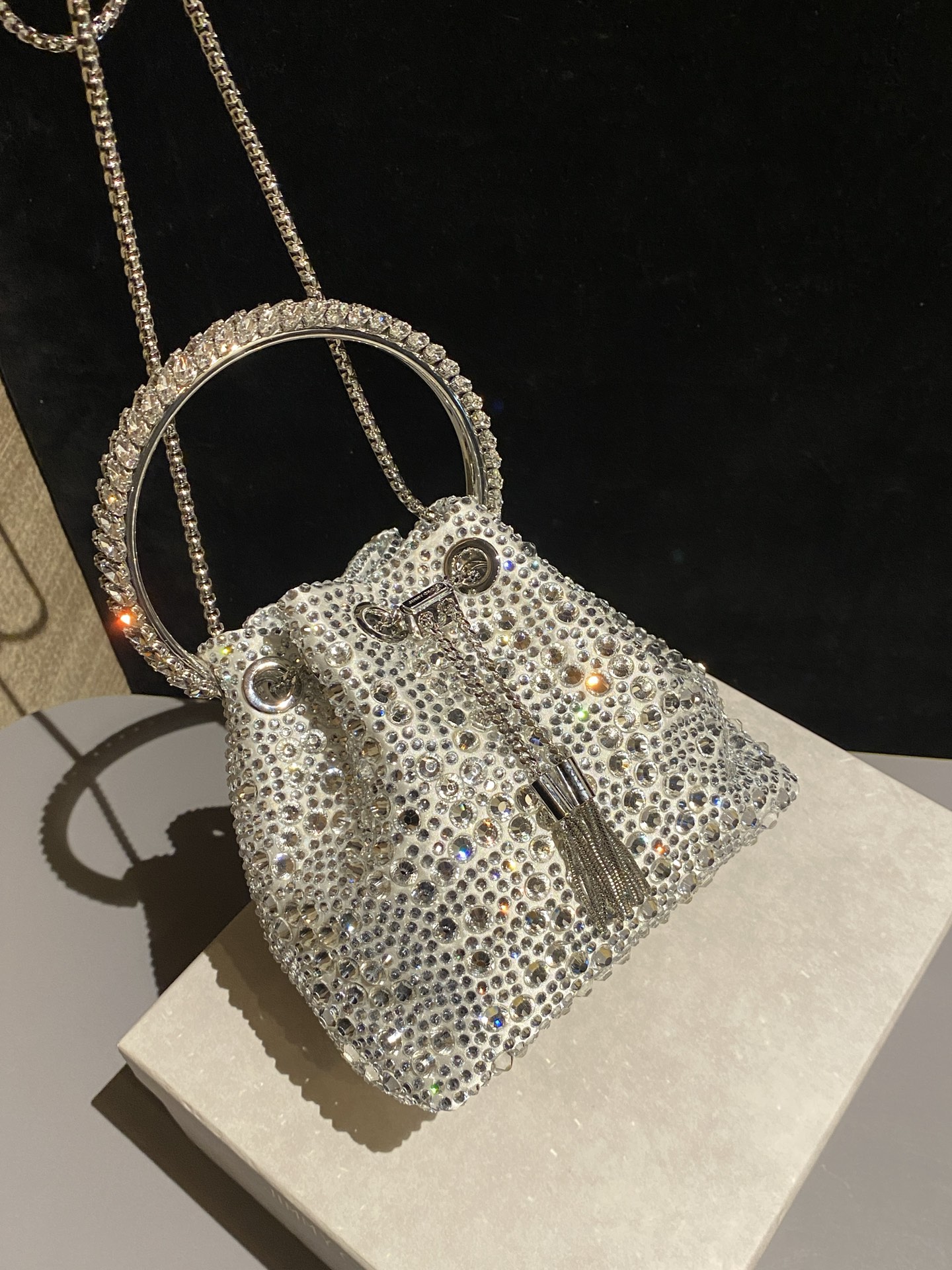 JIMMY CHOO
BON BON系列标志款手提包,光滑缎面铺嵌渐变水晶制作。
设计灵感源于软硬质感及甜美与张扬气质的强烈对比,点睛配以标志性金属流苏,成就如BON BON之名般个性别致又优雅迷人的时尚包袋。现代感桶包廓形,配以手环造型顶部提手,提手饰有百粒经三天精工颗颗细嵌的水晶,精美雅致,招牌奢华包袋当属本款BON BON手提包。
缎面烫钻水晶手嵌水晶饰手环提手Jimmy Choo logo压印金属流苏开合链条肩带内层口袋包袋尺寸:16(长)x15(高)x9.5(宽)厘米肩带长度:55厘米提手长度:9厘米 20259