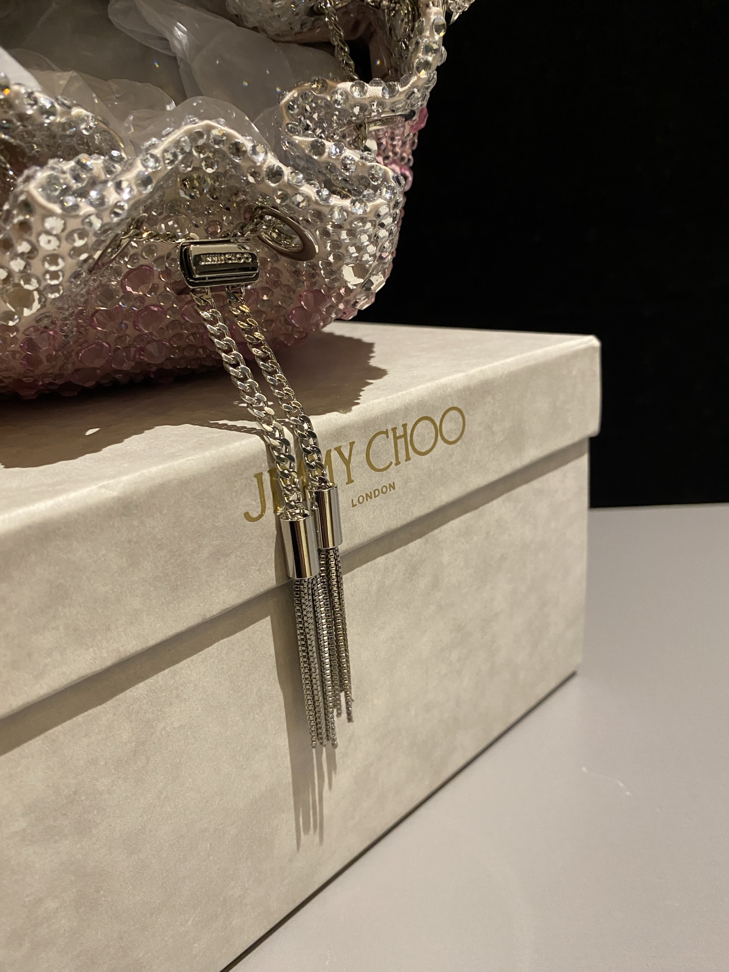 JIMMY CHOO
BON BON系列标志款手提包，光滑缎面铺嵌渐变水晶制作。
设计灵感源于软硬质感及甜美与张扬气质的强烈对比，点睛配以标志性金属流苏，成就如BON BON之名般个性别致又优雅迷人的时尚包袋。现代感桶包廓形，配以手环造型顶部提手，提手饰有百粒经三天精工颗颗细嵌的水晶，精美雅致，招牌奢华包袋当属本款BON BON手提包。
缎面烫钻水晶手嵌水晶饰手环提手Jimmy Choo logo压印金属流苏开合链条肩带内层口袋包袋尺寸：16（长）x15（高）x9.5（宽）厘米肩带长度：55厘米提手长度：9厘米 20259 