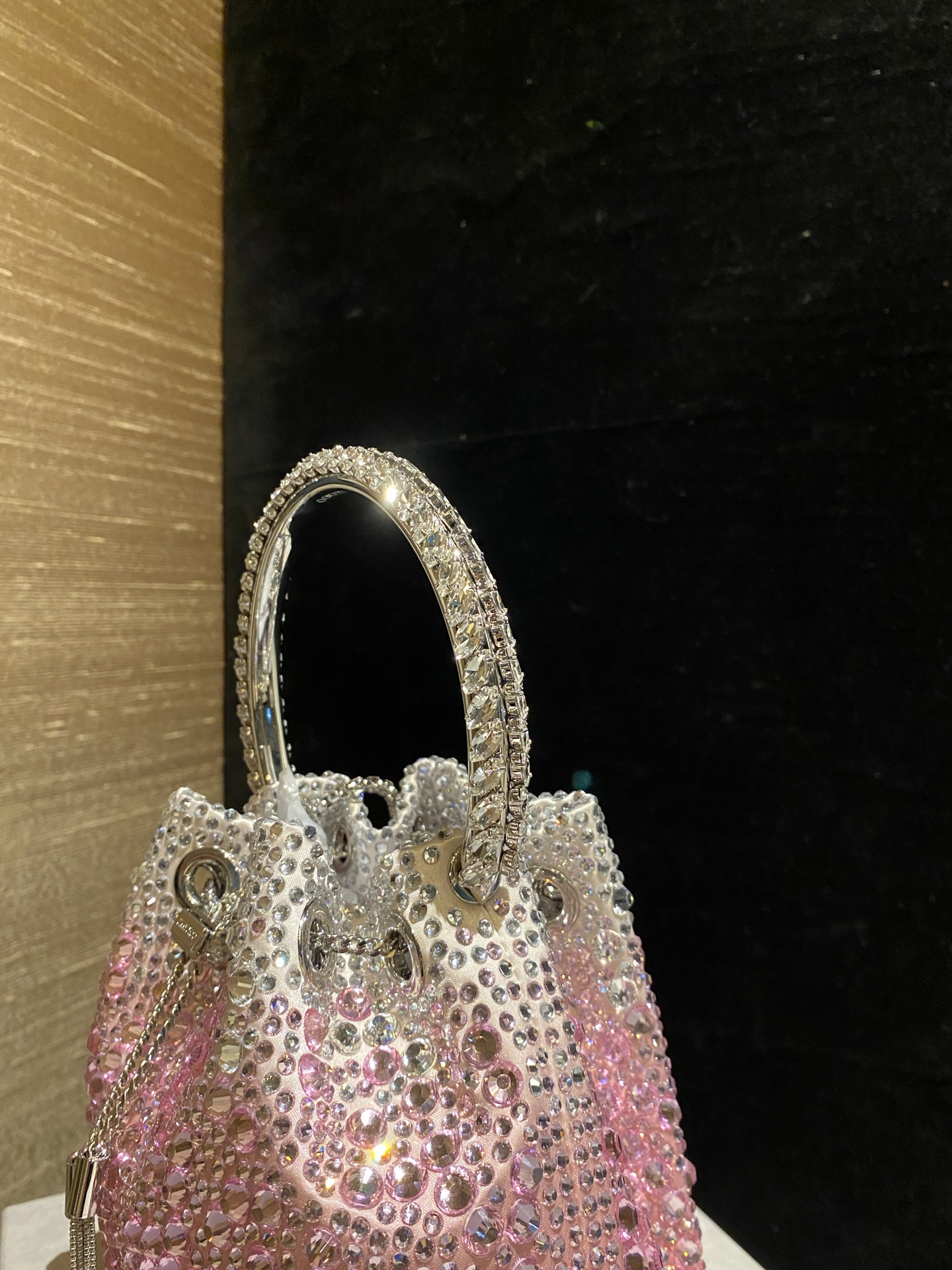 JIMMY CHOO
BON BON系列标志款手提包，光滑缎面铺嵌渐变水晶制作。
设计灵感源于软硬质感及甜美与张扬气质的强烈对比，点睛配以标志性金属流苏，成就如BON BON之名般个性别致又优雅迷人的时尚包袋。现代感桶包廓形，配以手环造型顶部提手，提手饰有百粒经三天精工颗颗细嵌的水晶，精美雅致，招牌奢华包袋当属本款BON BON手提包。
缎面烫钻水晶手嵌水晶饰手环提手Jimmy Choo logo压印金属流苏开合链条肩带内层口袋包袋尺寸：16（长）x15（高）x9.5（宽）厘米肩带长度：55厘米提手长度：9厘米 20259 