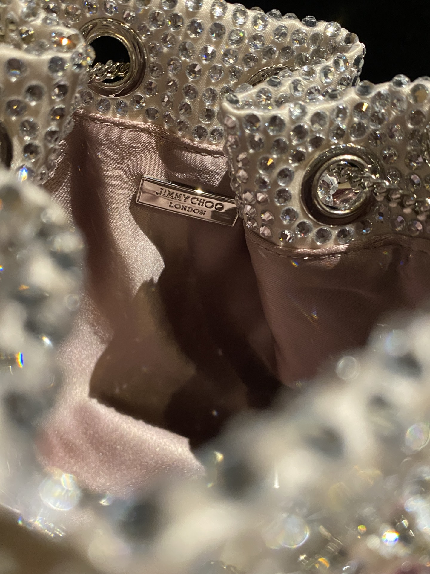 JIMMY CHOO
BON BON系列标志款手提包，光滑缎面铺嵌渐变水晶制作。
设计灵感源于软硬质感及甜美与张扬气质的强烈对比，点睛配以标志性金属流苏，成就如BON BON之名般个性别致又优雅迷人的时尚包袋。现代感桶包廓形，配以手环造型顶部提手，提手饰有百粒经三天精工颗颗细嵌的水晶，精美雅致，招牌奢华包袋当属本款BON BON手提包。
缎面烫钻水晶手嵌水晶饰手环提手Jimmy Choo logo压印金属流苏开合链条肩带内层口袋包袋尺寸：16（长）x15（高）x9.5（宽）厘米肩带长度：55厘米提手长度：9厘米 20259 