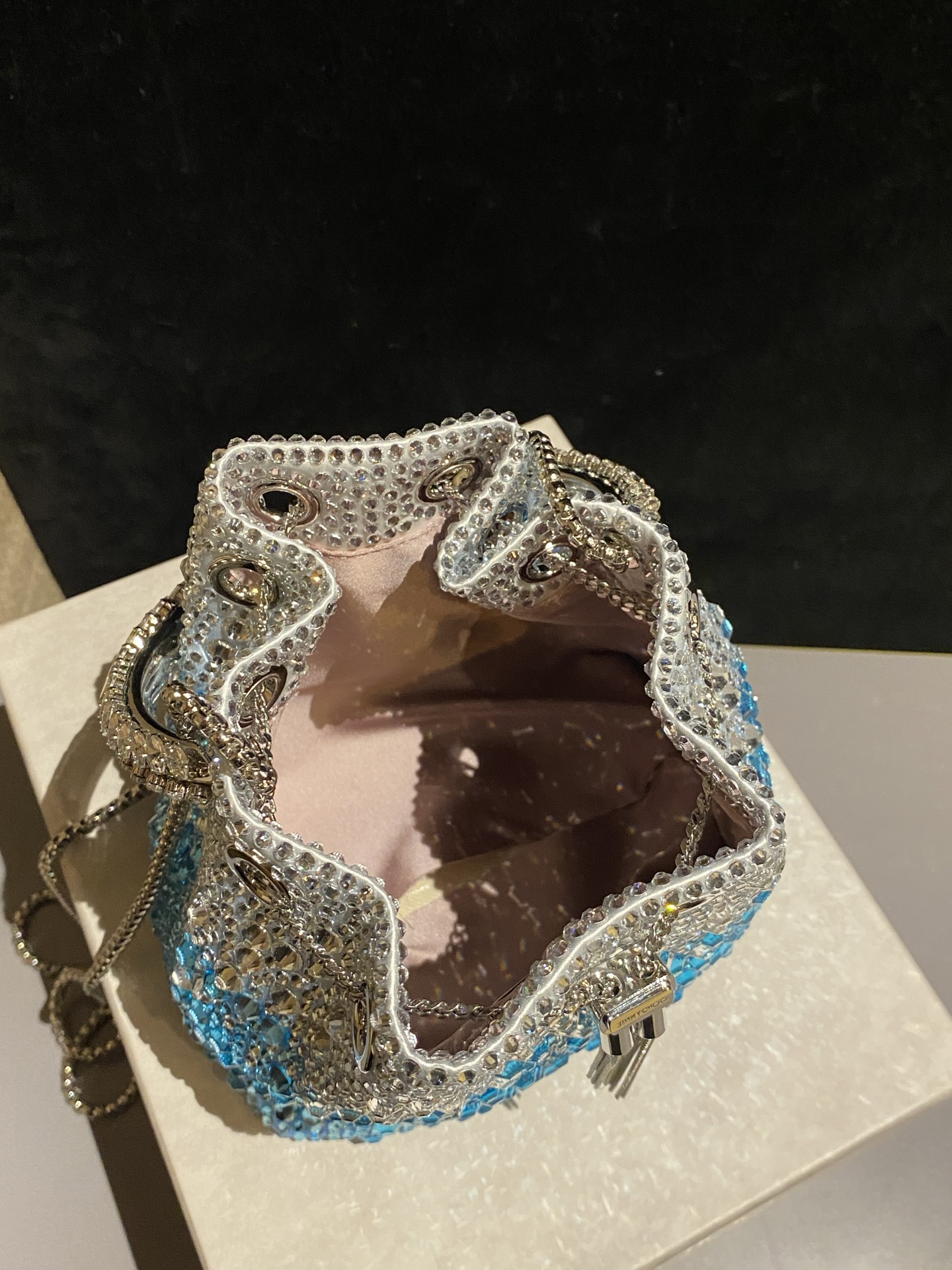 JIMMY CHOO
BON BON系列标志款手提包,光滑缎面铺嵌渐变水晶制作。
设计灵感源于软硬质感及甜美与张扬气质的强烈对比,点睛配以标志性金属流苏,成就如BON BON之名般个性别致又优雅迷人的时尚包袋。现代感桶包廓形,配以手环造型顶部提手,提手饰有百粒经三天精工颗颗细嵌的水晶,精美雅致,招牌奢华包袋当属本款BON BON手提包。
缎面烫钻水晶手嵌水晶饰手环提手Jimmy Choo logo压印金属流苏开合链条肩带内层口袋包袋尺寸:16(长)x15(高)x9.5(宽)厘米肩带长度:55厘米提手长度:9厘米 20259