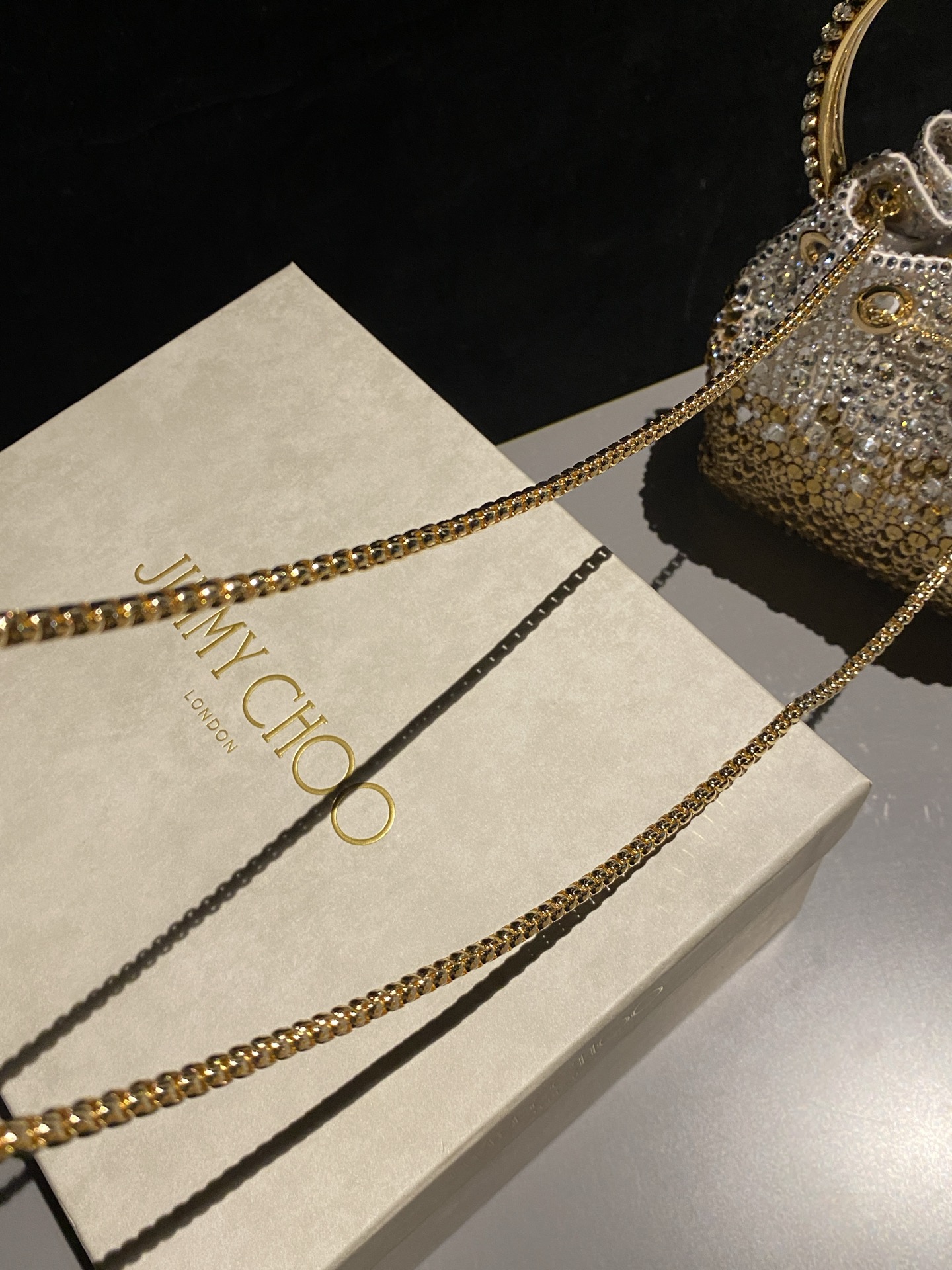 JIMMY CHOO
BON BON系列标志款手提包，光滑缎面铺嵌渐变水晶制作。
设计灵感源于软硬质感及甜美与张扬气质的强烈对比，点睛配以标志性金属流苏，成就如BON BON之名般个性别致又优雅迷人的时尚包袋。现代感桶包廓形，配以手环造型顶部提手，提手饰有百粒经三天精工颗颗细嵌的水晶，精美雅致，招牌奢华包袋当属本款BON BON手提包。
缎面烫钻水晶手嵌水晶饰手环提手Jimmy Choo logo压印金属流苏开合链条肩带内层口袋包袋尺寸：16（长）x15（高）x9.5（宽）厘米肩带长度：55厘米提手长度：9厘米 20259 