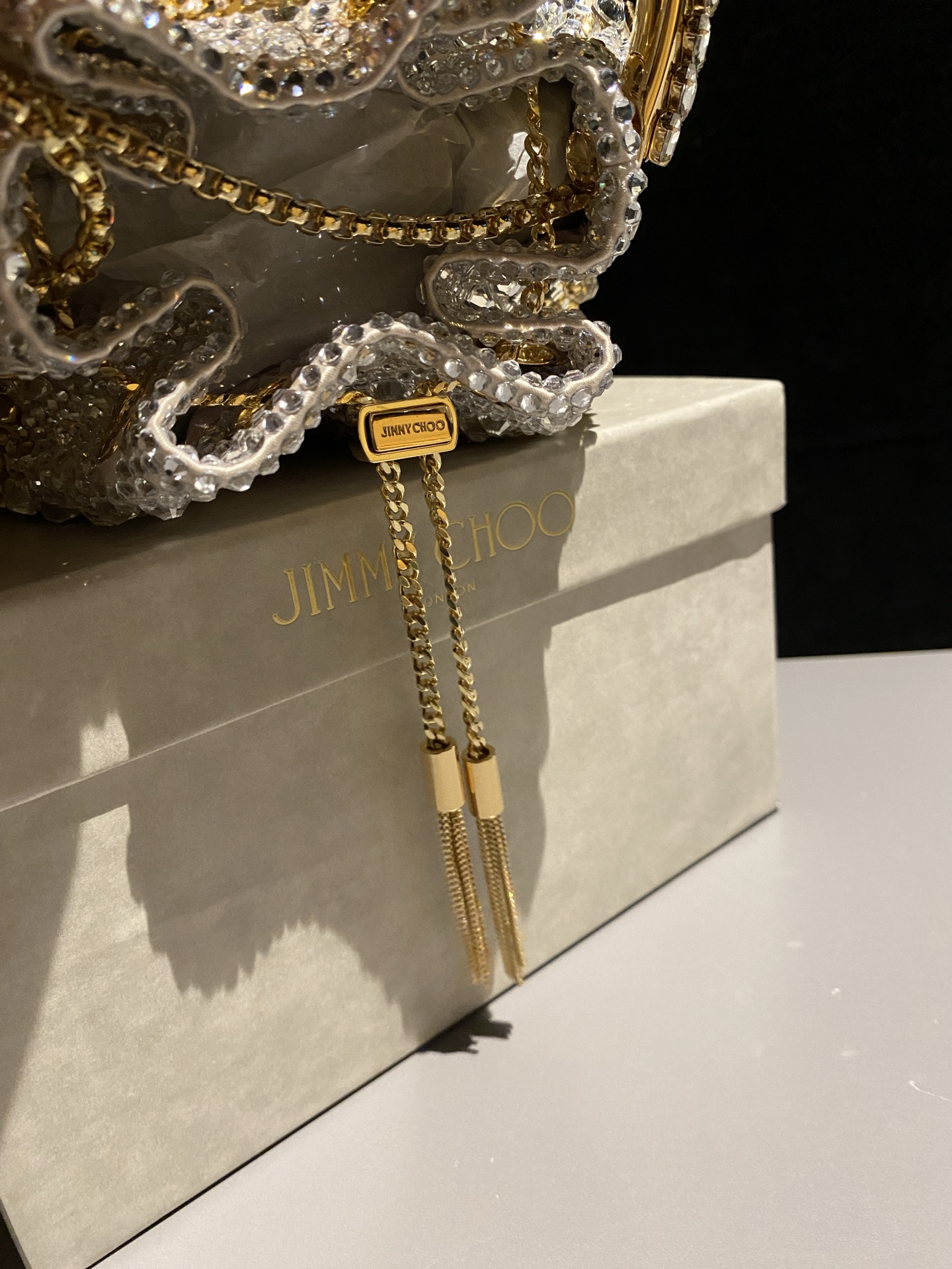JIMMY CHOO
BON BON系列标志款手提包，光滑缎面铺嵌渐变水晶制作。
设计灵感源于软硬质感及甜美与张扬气质的强烈对比，点睛配以标志性金属流苏，成就如BON BON之名般个性别致又优雅迷人的时尚包袋。现代感桶包廓形，配以手环造型顶部提手，提手饰有百粒经三天精工颗颗细嵌的水晶，精美雅致，招牌奢华包袋当属本款BON BON手提包。
缎面烫钻水晶手嵌水晶饰手环提手Jimmy Choo logo压印金属流苏开合链条肩带内层口袋包袋尺寸：16（长）x15（高）x9.5（宽）厘米肩带长度：55厘米提手长度：9厘米 20259 