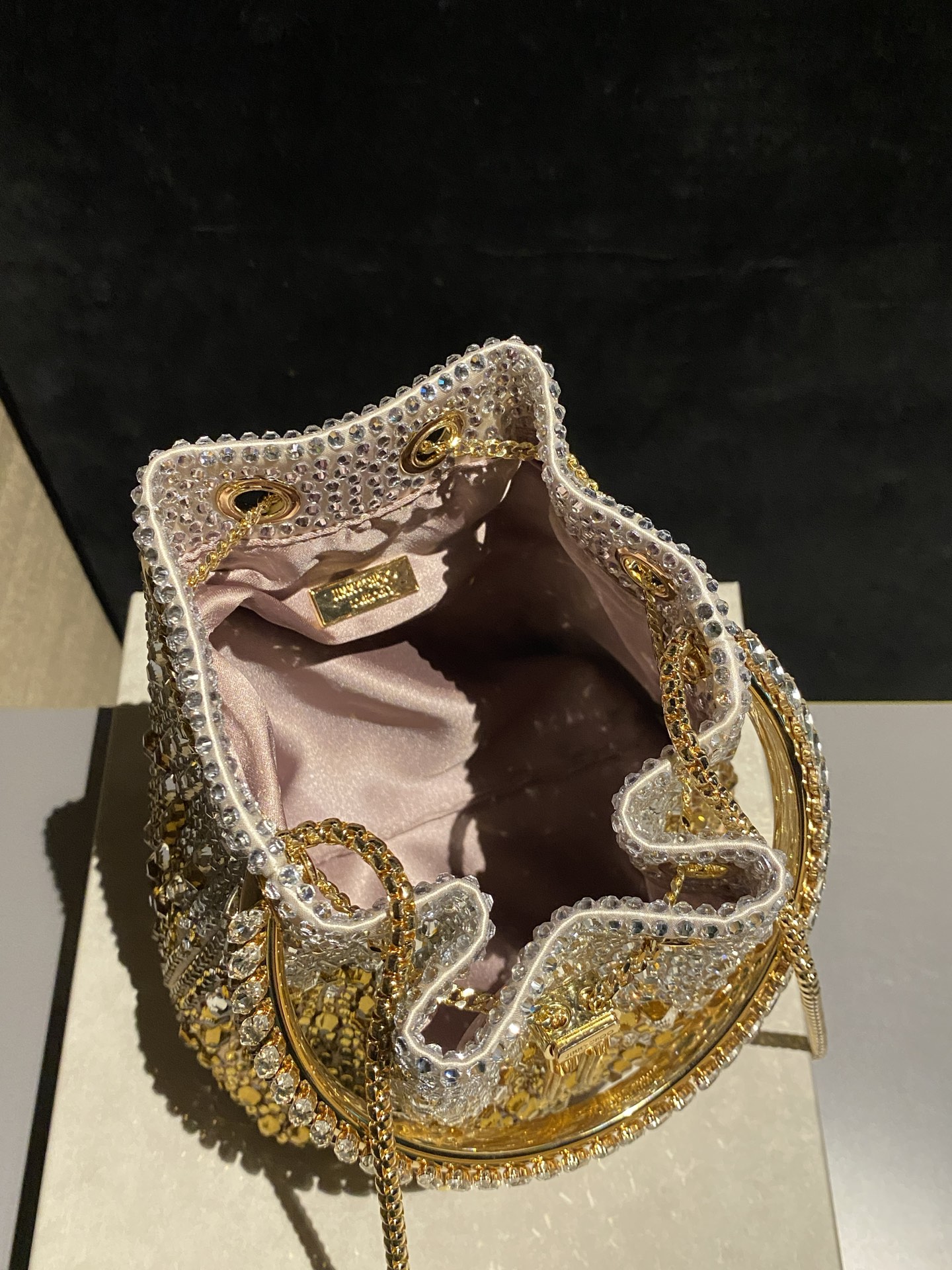 JIMMY CHOO
BON BON系列标志款手提包，光滑缎面铺嵌渐变水晶制作。
设计灵感源于软硬质感及甜美与张扬气质的强烈对比，点睛配以标志性金属流苏，成就如BON BON之名般个性别致又优雅迷人的时尚包袋。现代感桶包廓形，配以手环造型顶部提手，提手饰有百粒经三天精工颗颗细嵌的水晶，精美雅致，招牌奢华包袋当属本款BON BON手提包。
缎面烫钻水晶手嵌水晶饰手环提手Jimmy Choo logo压印金属流苏开合链条肩带内层口袋包袋尺寸：16（长）x15（高）x9.5（宽）厘米肩带长度：55厘米提手长度：9厘米 20259 