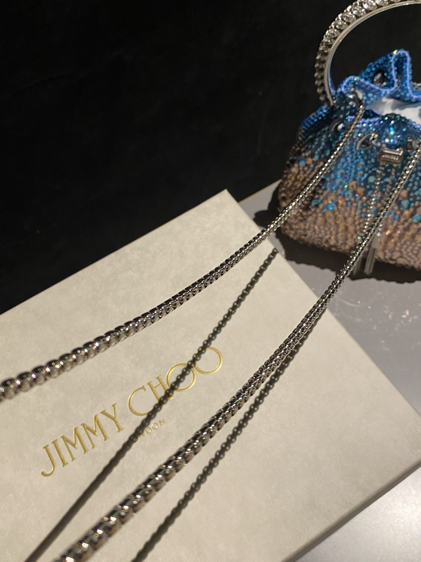 JIMMY CHOO
BON BON系列标志款手提包,光滑缎面铺嵌渐变水晶制作。
设计灵感源于软硬质感及甜美与张扬气质的强烈对比,点睛配以标志性金属流苏,成就如BON BON之名般个性别致又优雅迷人的时尚包袋。现代感桶包廓形,配以手环造型顶部提手,提手饰有百粒经三天精工颗颗细嵌的水晶,精美雅致,招牌奢华包袋当属本款BON BON手提包。
缎面烫钻水晶手嵌水晶饰手环提手Jimmy Choo logo压印金属流苏开合链条肩带内层口袋包袋尺寸:16(长)x15(高)x9.5(宽)厘米肩带长度:55厘米提手长度:9厘米 20259
