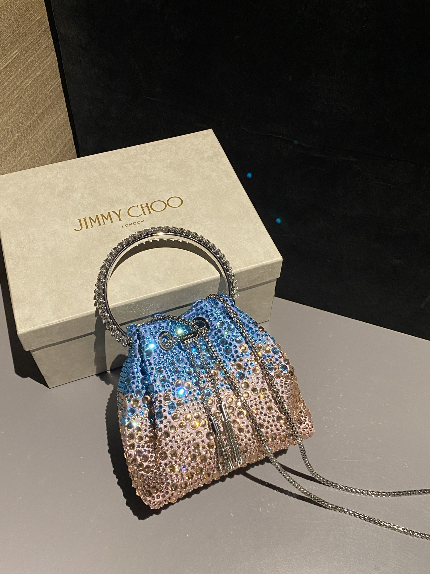 JIMMY CHOO
BON BON系列标志款手提包,光滑缎面铺嵌渐变水晶制作。
设计灵感源于软硬质感及甜美与张扬气质的强烈对比,点睛配以标志性金属流苏,成就如BON BON之名般个性别致又优雅迷人的时尚包袋。现代感桶包廓形,配以手环造型顶部提手,提手饰有百粒经三天精工颗颗细嵌的水晶,精美雅致,招牌奢华包袋当属本款BON BON手提包。
缎面烫钻水晶手嵌水晶饰手环提手Jimmy Choo logo压印金属流苏开合链条肩带内层口袋包袋尺寸:16(长)x15(高)x9.5(宽)厘米肩带长度:55厘米提手长度:9厘米 20259