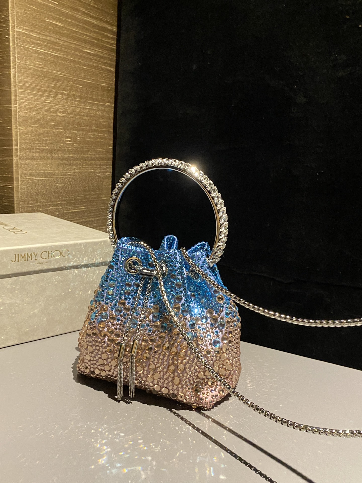 JIMMY CHOO
BON BON系列标志款手提包,光滑缎面铺嵌渐变水晶制作。
设计灵感源于软硬质感及甜美与张扬气质的强烈对比,点睛配以标志性金属流苏,成就如BON BON之名般个性别致又优雅迷人的时尚包袋。现代感桶包廓形,配以手环造型顶部提手,提手饰有百粒经三天精工颗颗细嵌的水晶,精美雅致,招牌奢华包袋当属本款BON BON手提包。
缎面烫钻水晶手嵌水晶饰手环提手Jimmy Choo logo压印金属流苏开合链条肩带内层口袋包袋尺寸:16(长)x15(高)x9.5(宽)厘米肩带长度:55厘米提手长度:9厘米 20259