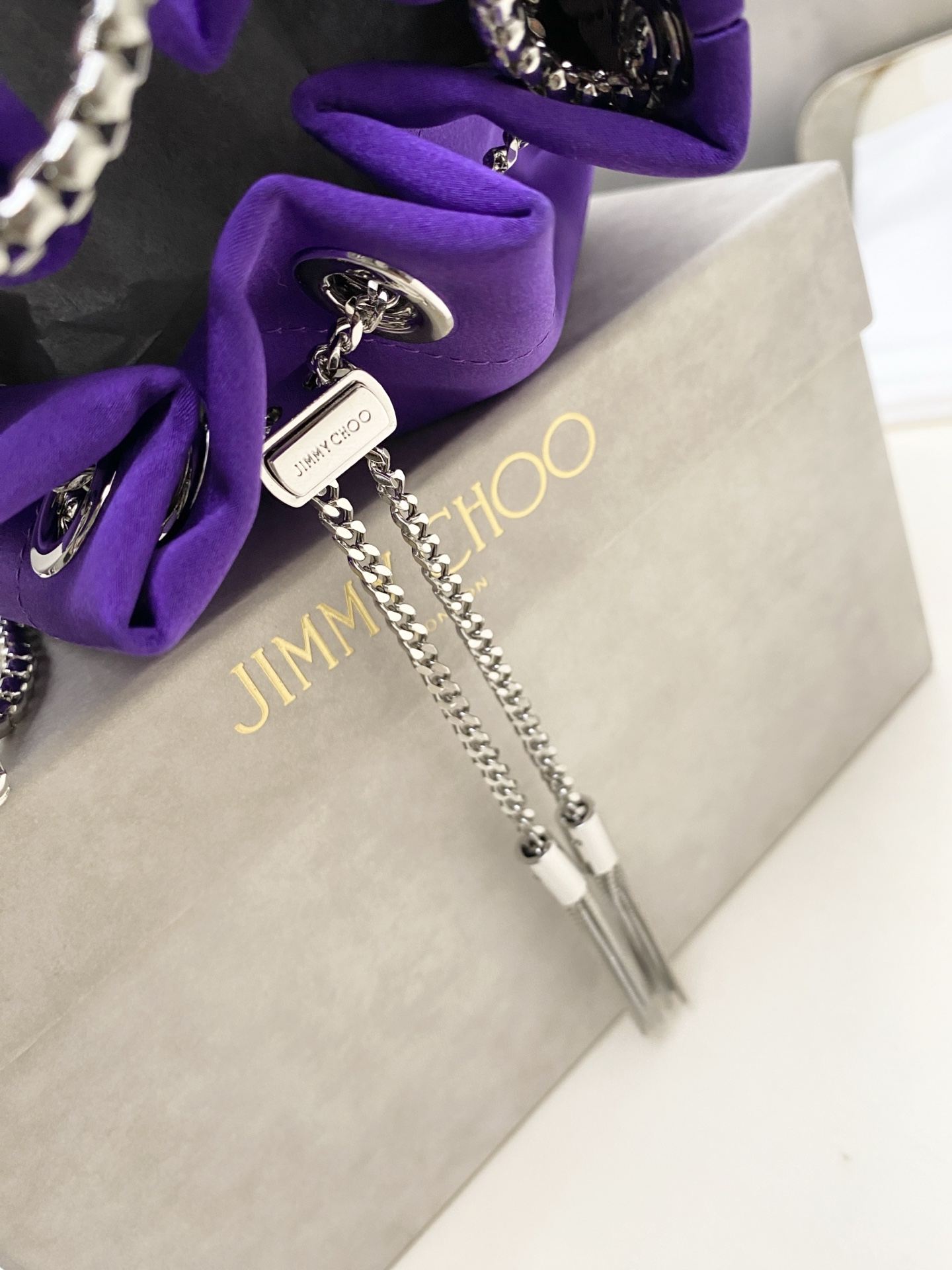 JIMMY CHOO绸缎
BON BON系列标志款手提包，光滑缎面
设计灵感源于软硬质感及甜美与张扬气质的强烈对比，点睛配以标志性金属流苏，成就如BON BON之名般个性别致又优雅迷人的时尚包袋。现代感桶包廓形，配以手环造型顶部提手，提手饰有百粒经三天精工颗颗细嵌的水晶，精美雅致，招牌奢华包袋当属本款BON BON手提包。
缎面烫钻水晶手嵌水晶饰手环提手Jimmy Choo logo压印金属流苏开合链条肩带内层口袋包袋尺寸：16（长）x15（高）x9.5（宽）厘米肩带长度：55厘米提手长度：9厘米 20263