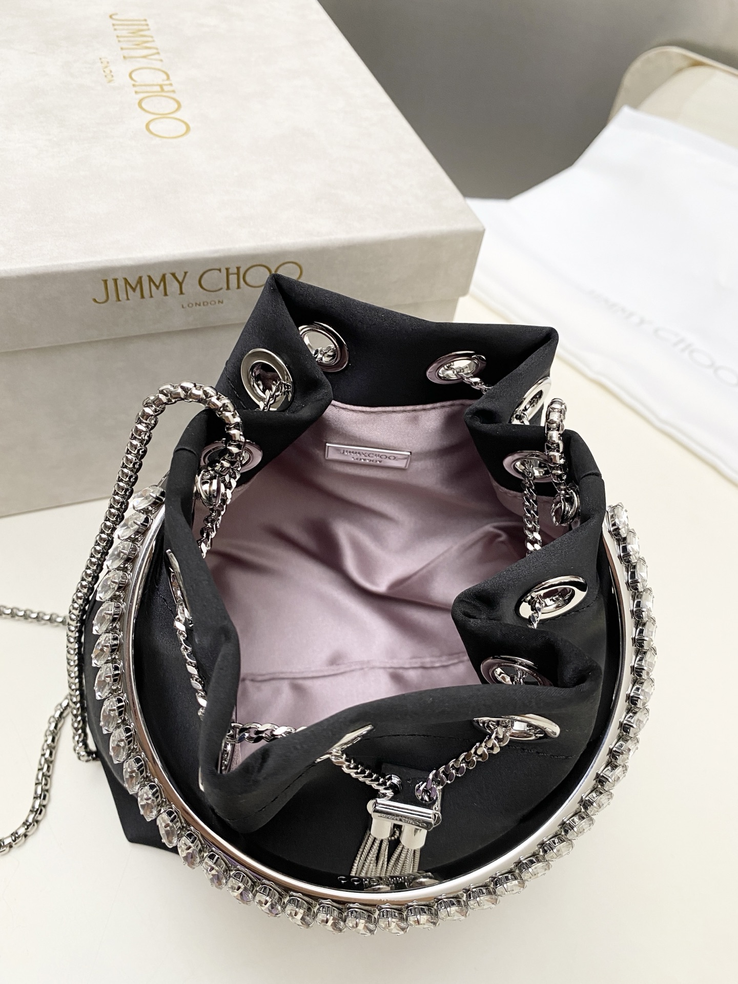 JIMMY CHOO绸缎
BON BON系列标志款手提包,光滑缎面
设计灵感源于软硬质感及甜美与张扬气质的强烈对比,点睛配以标志性金属流苏,成就如BON BON之名般个性别致又优雅迷人的时尚包袋。现代感桶包廓形,配以手环造型顶部提手,提手饰有百粒经三天精工颗颗细嵌的水晶,精美雅致,招牌奢华包袋当属本款BON BON手提包。
缎面烫钻水晶手嵌水晶饰手环提手Jimmy Choo logo压印金属流苏开合链条肩带内层口袋包袋尺寸:16(长)x15(高)x9.5(宽)厘米肩带长度:55厘米提手长度:9厘米 20263