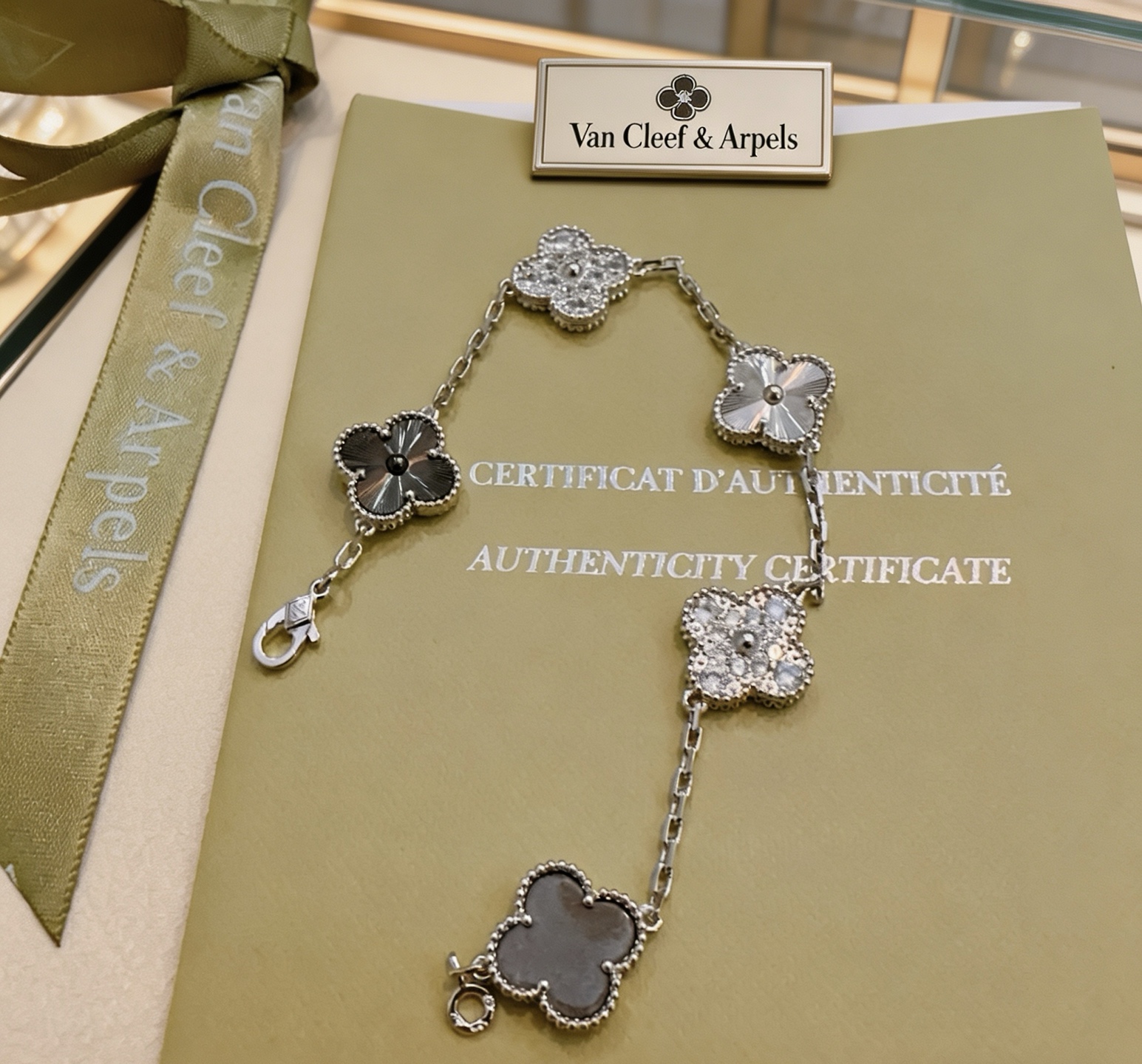 Van Cleef Arpels Bracelet Alhambra Métal argenté avec pierres transparentes ressemblant à des diamants Pierre gris foncé Métal guilloché argenté et incrustations de trèfle gris foncé 19 cm