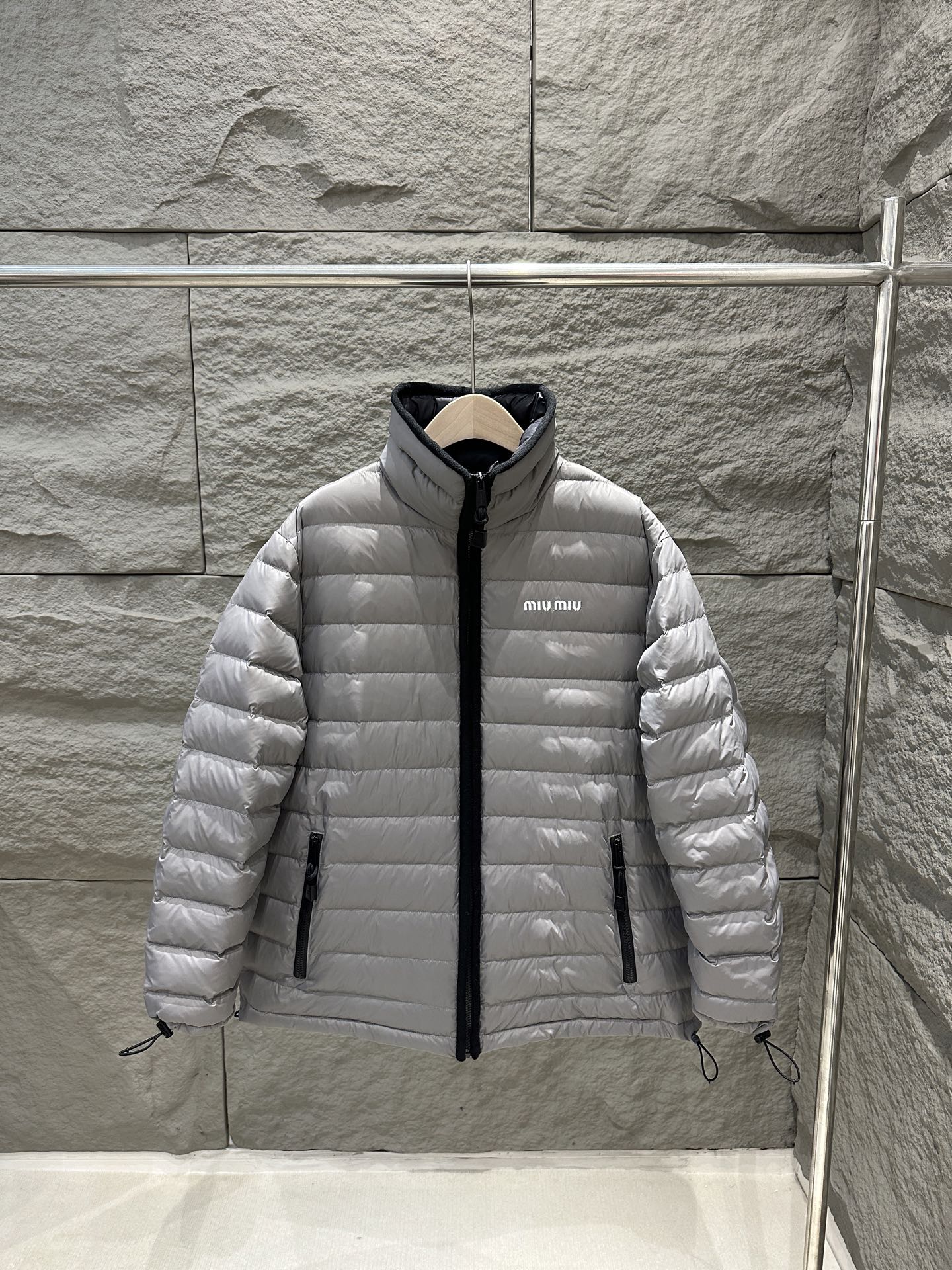 NO:629025,Comes with dust bag MiuMiu 25 new autumn and winter ribbed stand-up collar down jacket, the same style for men and women. The oversize version is not flattering and explores the winter elegance of MiuMiu. This gray and white steel down jacket is designed with clean lines and a stand-up collar to interpret simplicity and fashion. The collar and placket are edged with black cashmere. The side pockets are practical, and the cuffs and hem have elastic drawstrings. It is windproof and adjustable. White brand letters are embroidered on the left chest.  It highlights the recognition and embodies the rebellious spirit of Miu Miu. It has the original color and open mold puller, a full set of accessories, and 90 velvet light filling to add comfort and style. The loose version is more lazy and comfortable. The high-end texture and simple style perfectly blend, making it a must-have fashion item in the cold season. Color: gray and white steel, size S/M/L,, miumiu, versace, down jacket, alexander wang19860909配防尘袋MiuMiu 25秋冬新款 排骨立领羽绒服,男女同款 oversize版型不挑身材,探索MiuMiu的冬日优雅,这款灰白钢色羽绒服以利落线条和立领设计,诠释简约时尚.领口与门襟均以黑色羊绒包边 侧边口袋兼顾实用,袖口与下摆均有弹力抽绳 防风又可调节松紧.左胸白色品牌字母刺绣 彰显辨识度,体现MiuMiu的叛逆精神,原版打色 开模拉头,全套辅料,90绒轻盈填充增添舒适与风格,宽松版型更显慵懒自在,高级质感与简约风格完美交融,成为寒冷季节的必备时尚单品.颜色灰白钢色,尺码S/M/L,,miumiu,versace,down jacket,alexander wang,Women's clothing